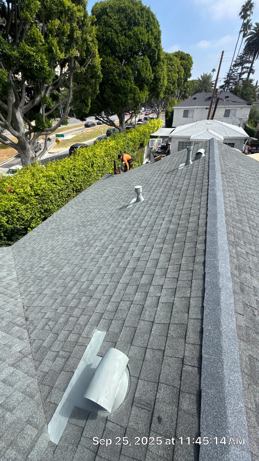 Worker installing gray asphalt shingle roof with pipe vents in Beverly Hills | Roof Replacement Inc worker installing gray asphalt shingle roof with pipe vents — Beverly Hills — Roof Replacement Inc