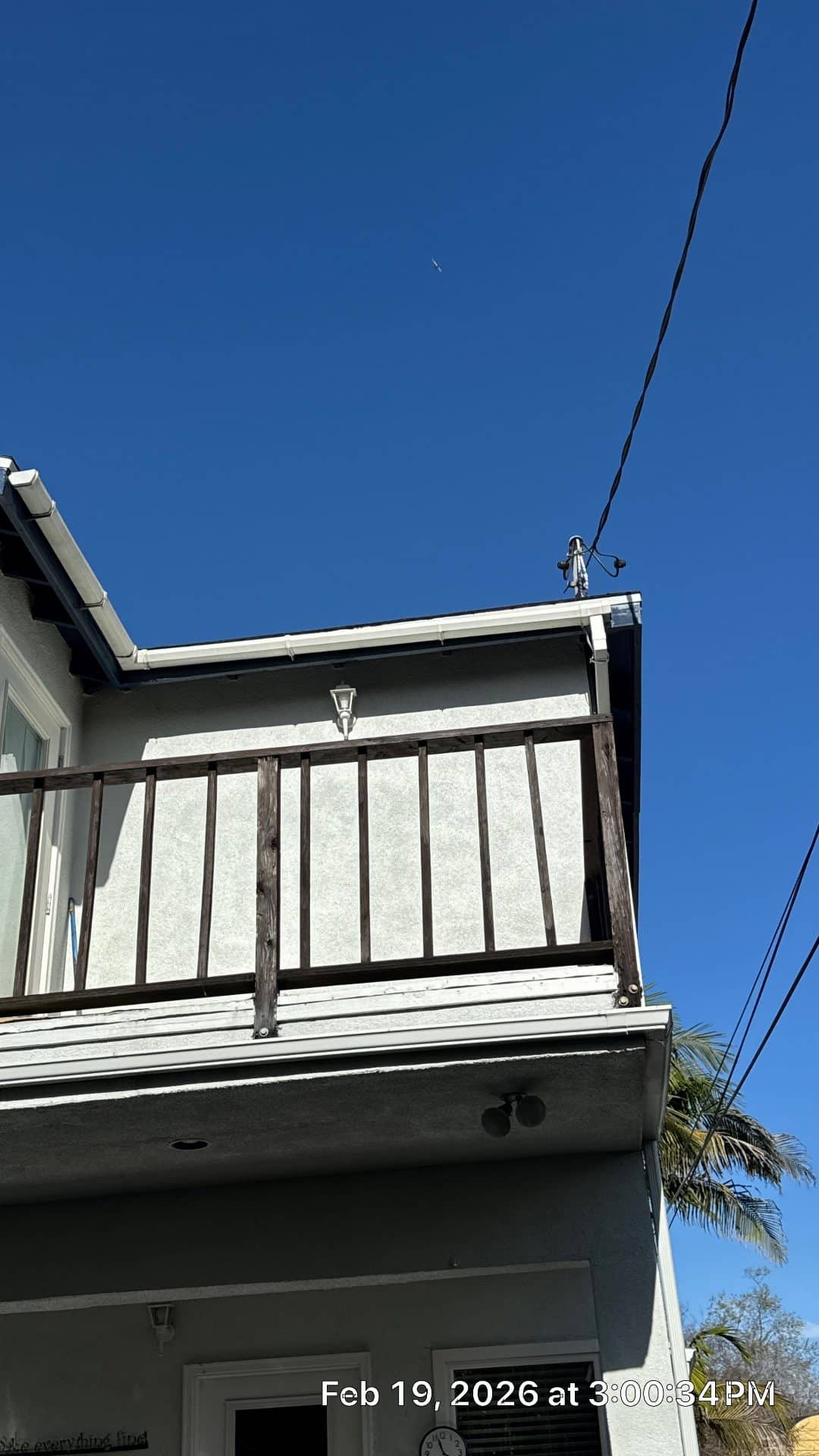Two-story stucco building with wood balcony railing, gutters, fascia — Roof Replacement Inc