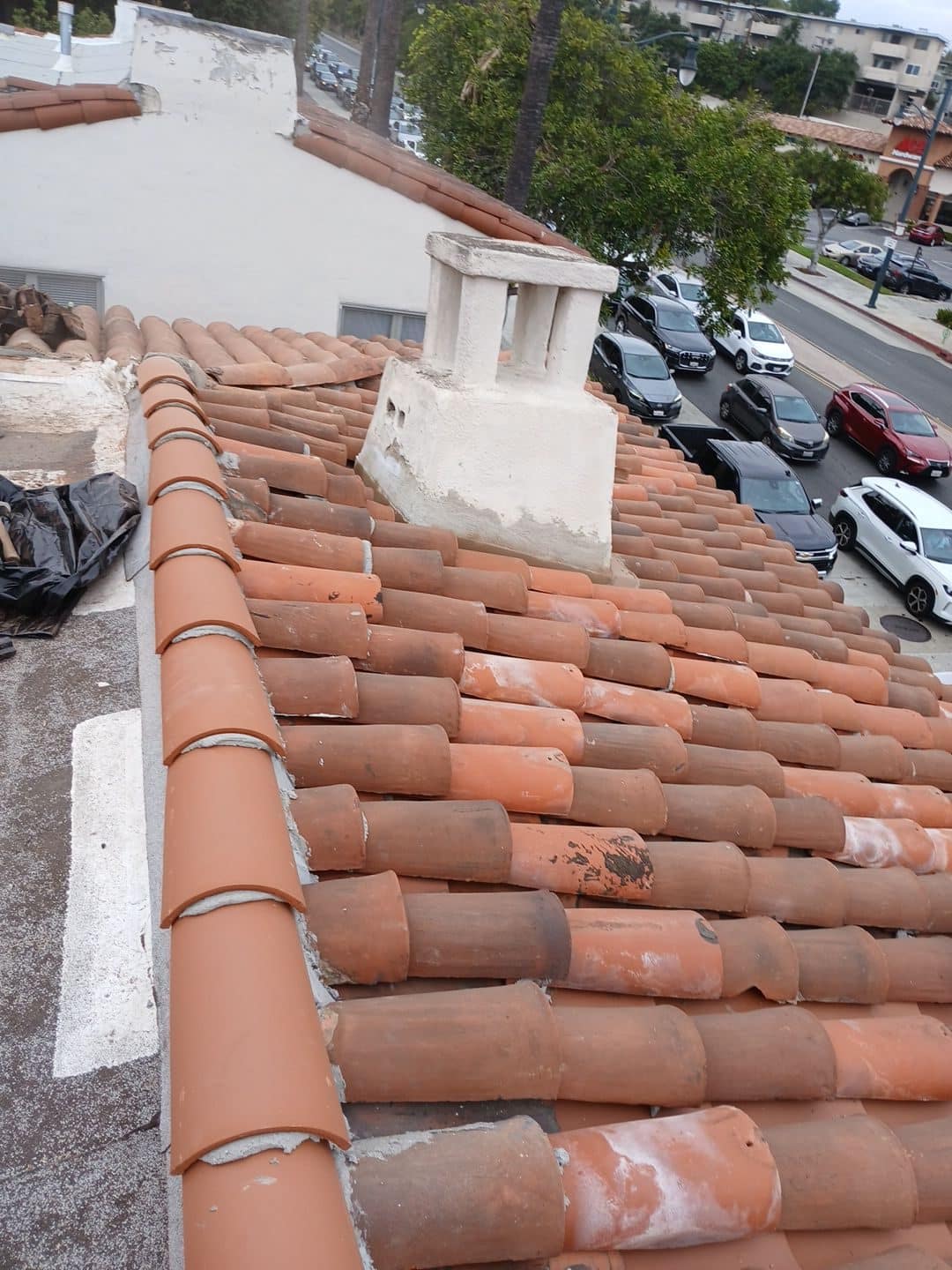 Spanish clay barrel tile roof with stucco chimney, street below | Roof Replacement Inc Spanish clay barrel tile roof with stucco chimney, street below — Roof Replacement Inc