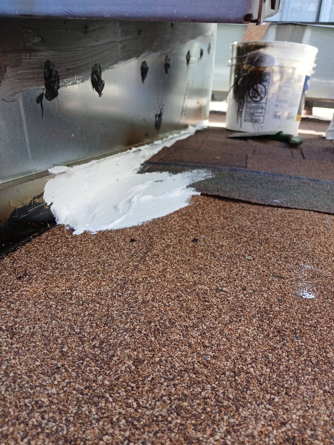 White sealant applied at metal wall base flashing over gravel built-up roof | Roof Replacement Inc White sealant applied at metal wall base flashing over gravel built-up roof — Roof Replacement Inc