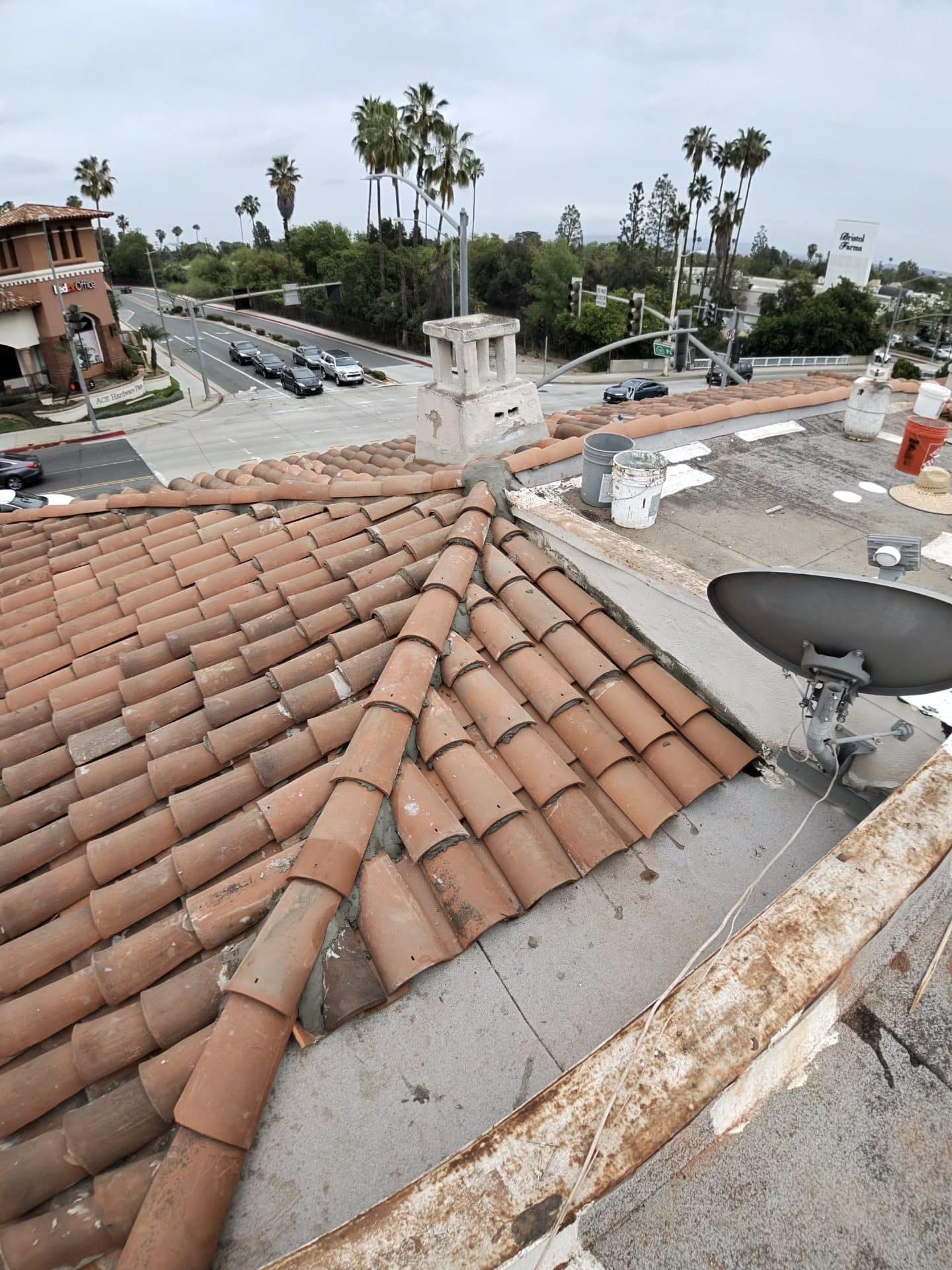Clay barrel tile roof with chimney cap and satellite dish — Roof Replacement Inc