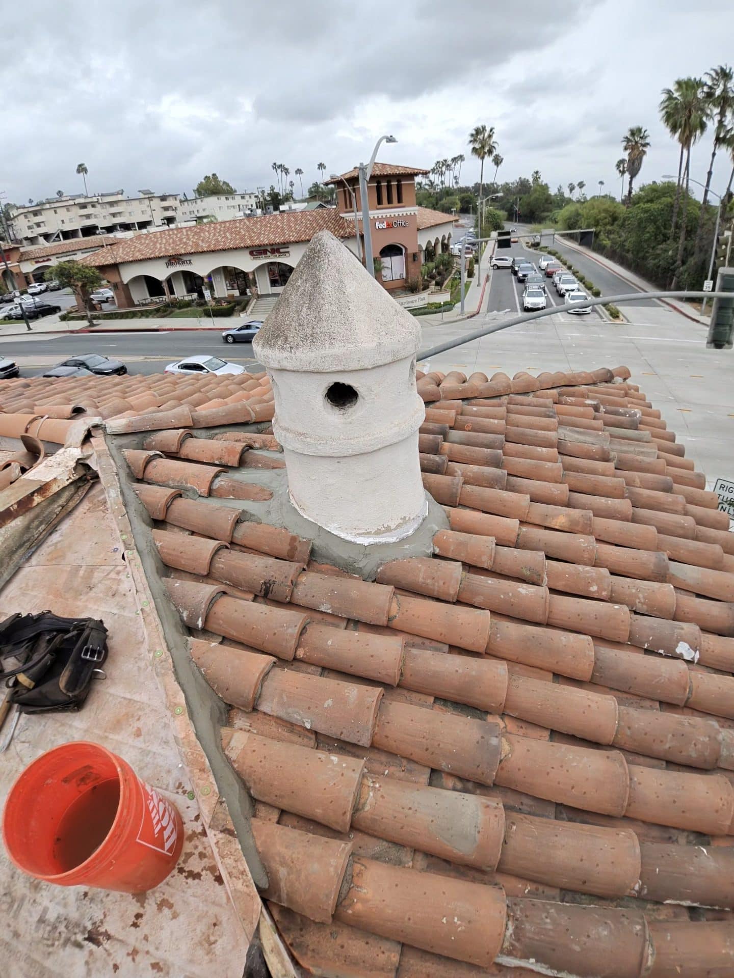 Clay barrel tile roof with stucco chimney cap under repair | Roof Replacement Inc Clay barrel tile roof with stucco chimney cap under repair — Roof Replacement Inc