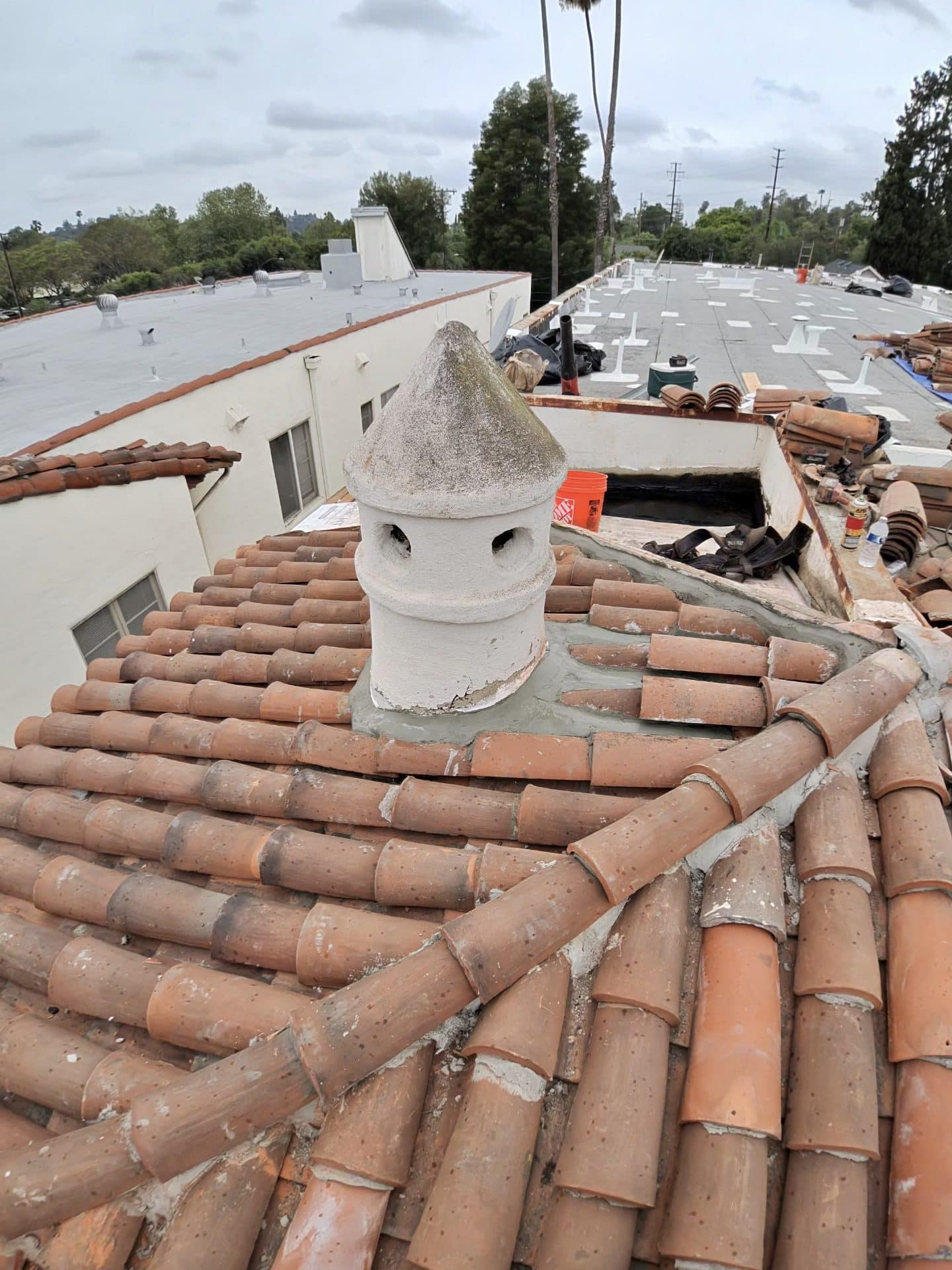 Clay barrel tile roof with decorative chimney pot under repair — Roof Replacement Inc