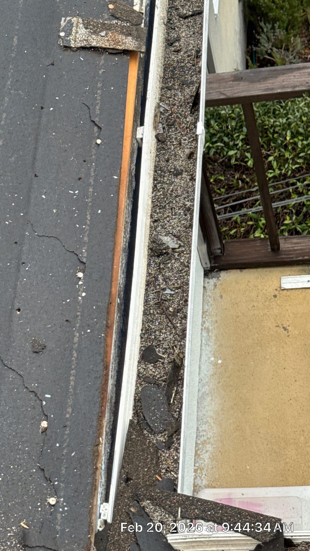 Clogged aluminum gutter filled with debris on low-slope roof edge | Roof Replacement Inc Clogged aluminum gutter filled with debris on low-slope roof edge — Roof Replacement Inc