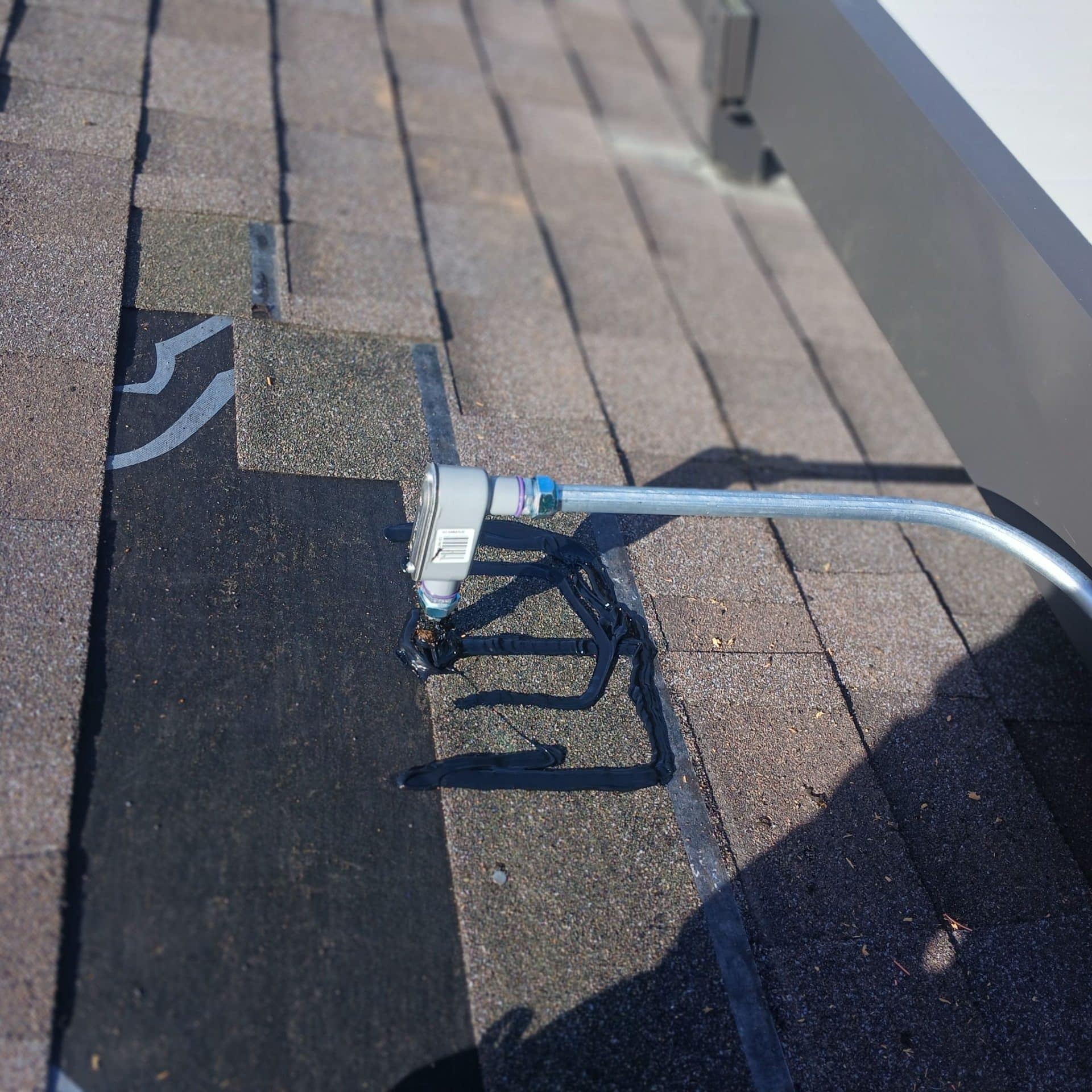 Asphalt shingle roof with conduit elbow sealed using roofing tar — Roof Replacement Inc