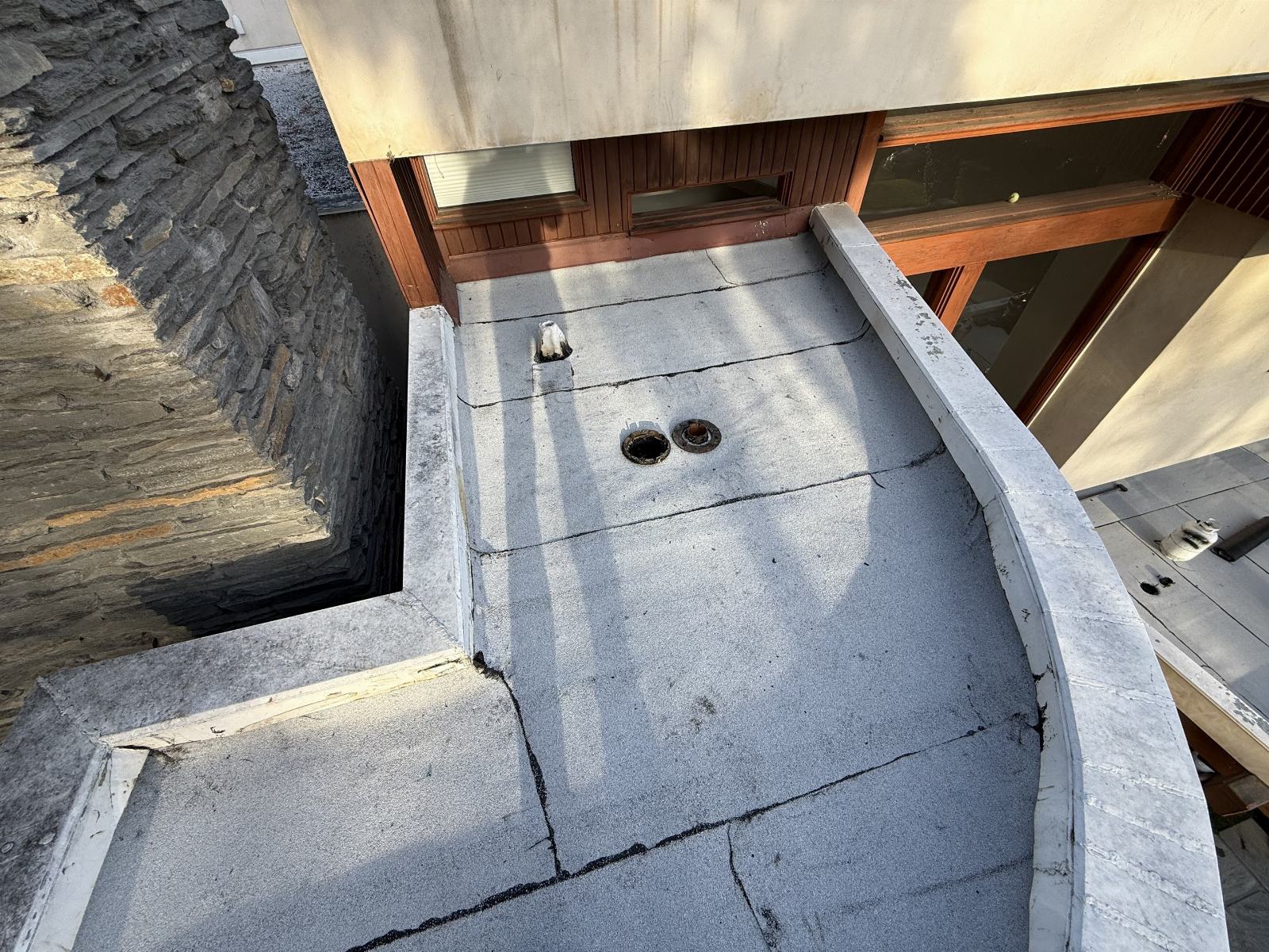 Cracked flat roof membrane with two drain openings and parapet wall in Beverly Hills | Roof Replacement Inc cracked flat roof membrane with two drain openings and parapet wall — Beverly Hills — Roof Replacement Inc