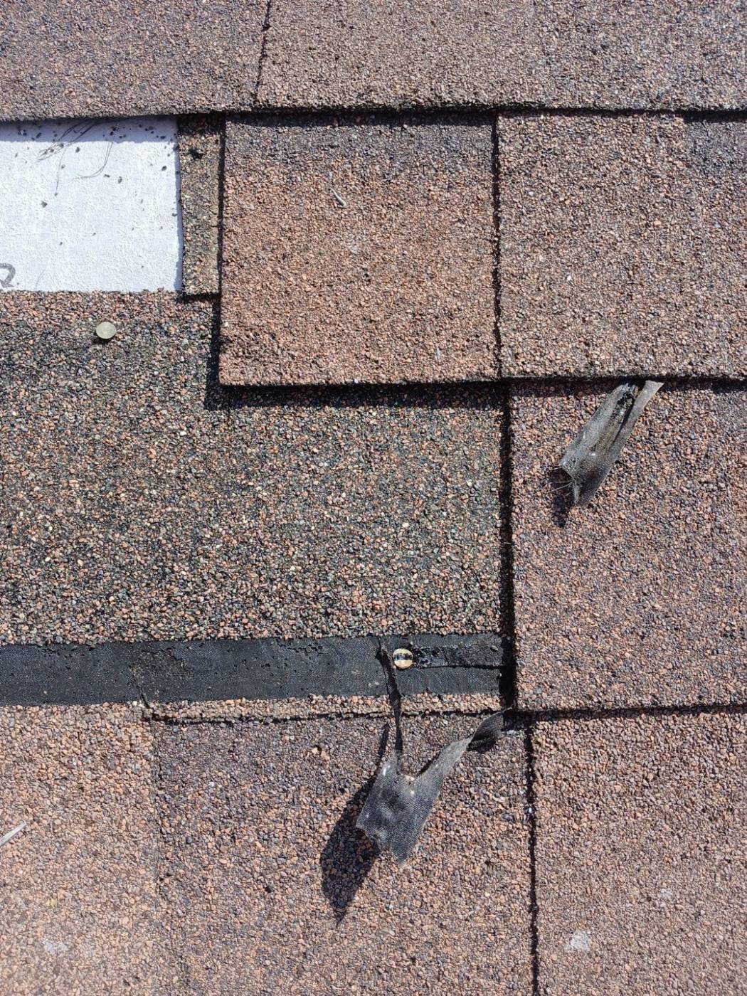Damaged asphalt shingles with lifted tabs and exposed underlayment | Roof Replacement Inc Damaged asphalt shingles with lifted tabs and exposed underlayment — Roof Replacement Inc