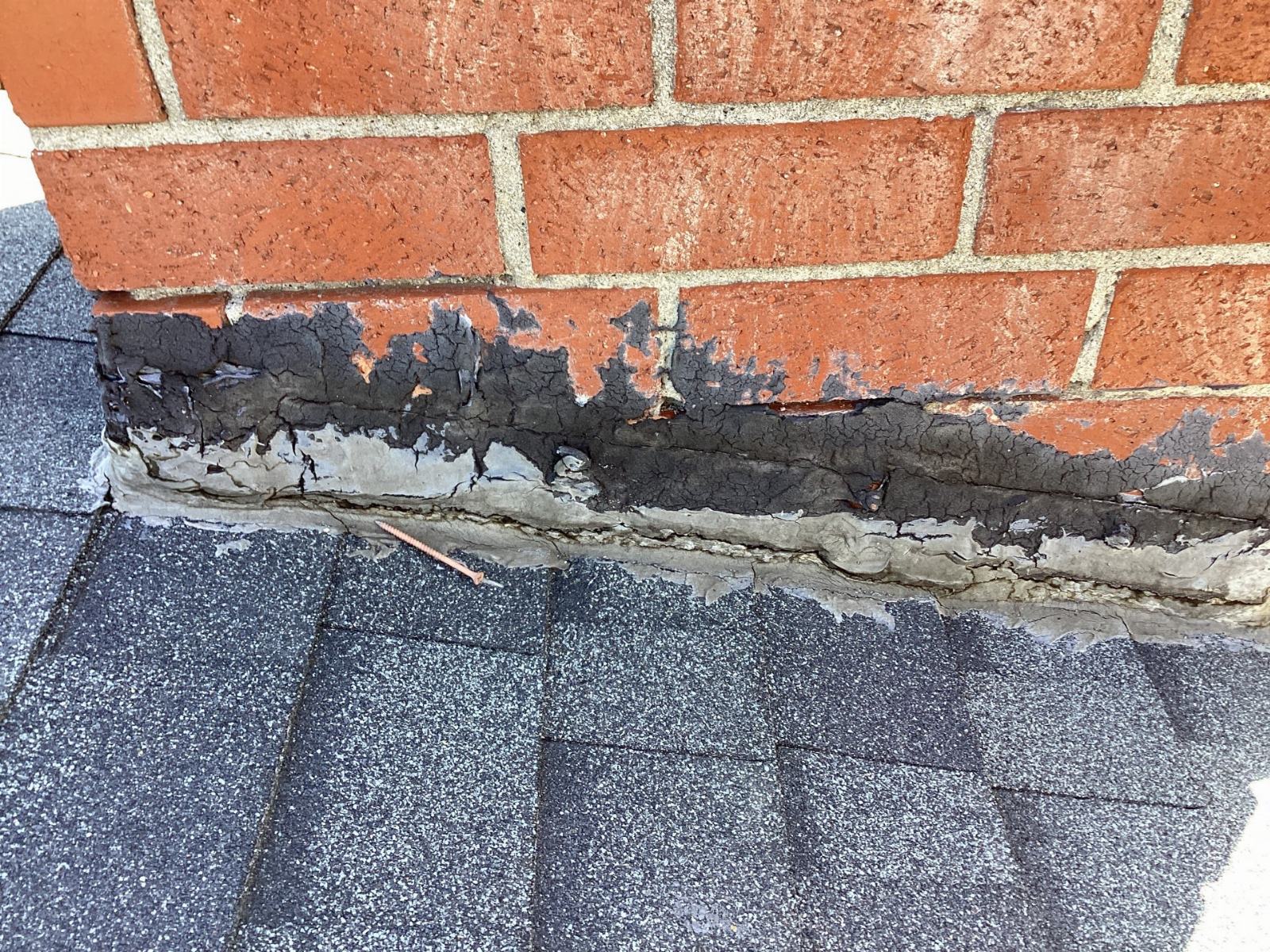 deteriorated tar flashing at brick chimney base on asphalt shingles — Calabasas — Roof Replacement Inc