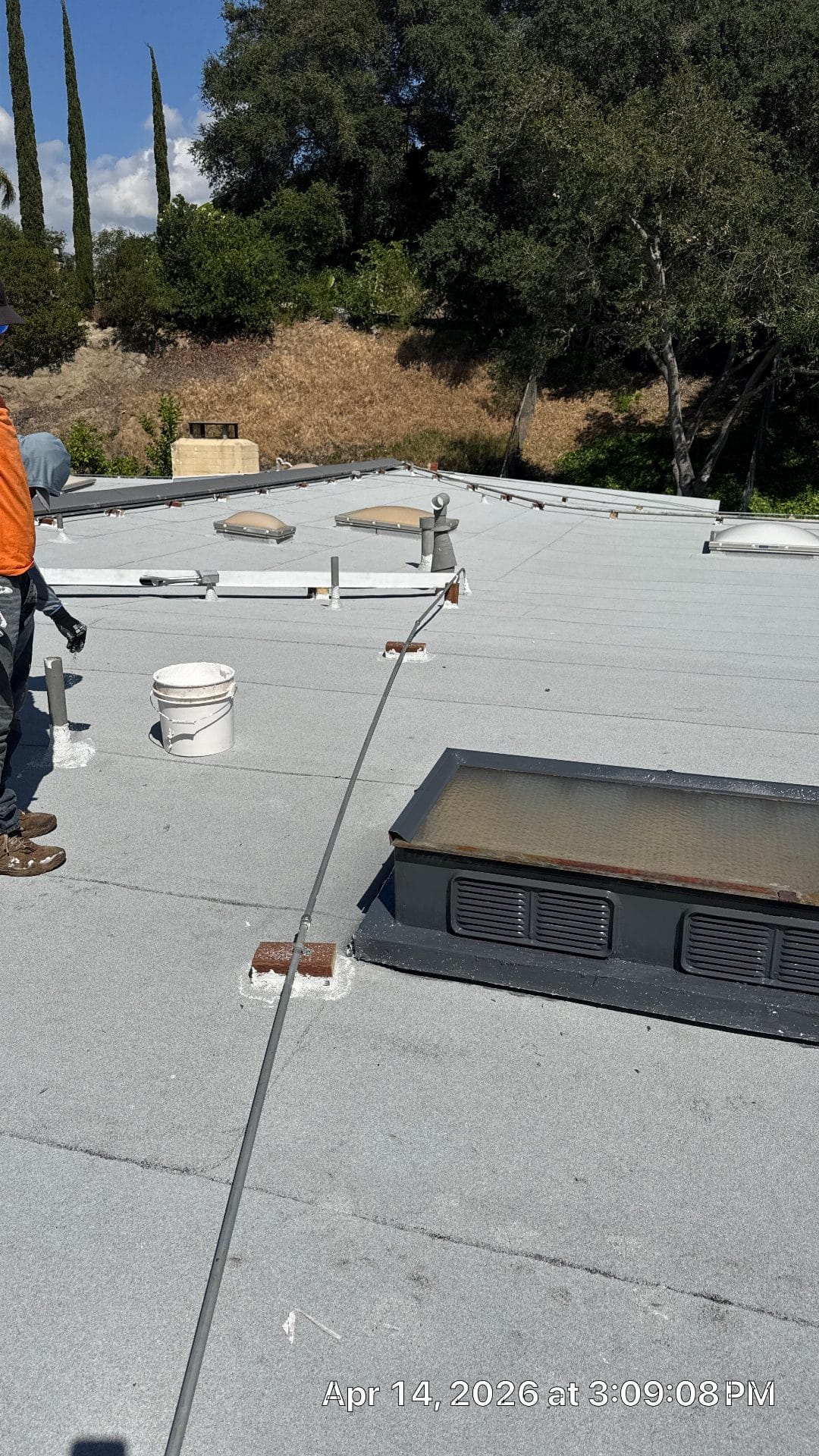 Workers applying white coating to flat roof with roller and bucket in La Cañada Flintridge | Roof Replacement Inc workers applying white coating to flat roof with roller and bucket — La Cañada Flintridge — Roof Replacement Inc