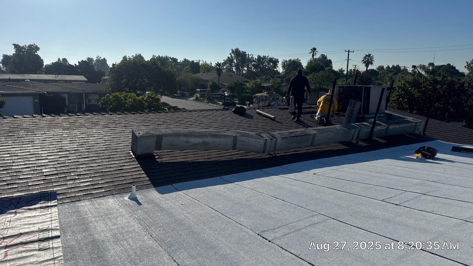 Flat modified bitumen roof with shingle slope; two workers on deck | Roof Replacement Inc Flat modified bitumen roof with shingle slope; two workers on deck — Roof Replacement Inc