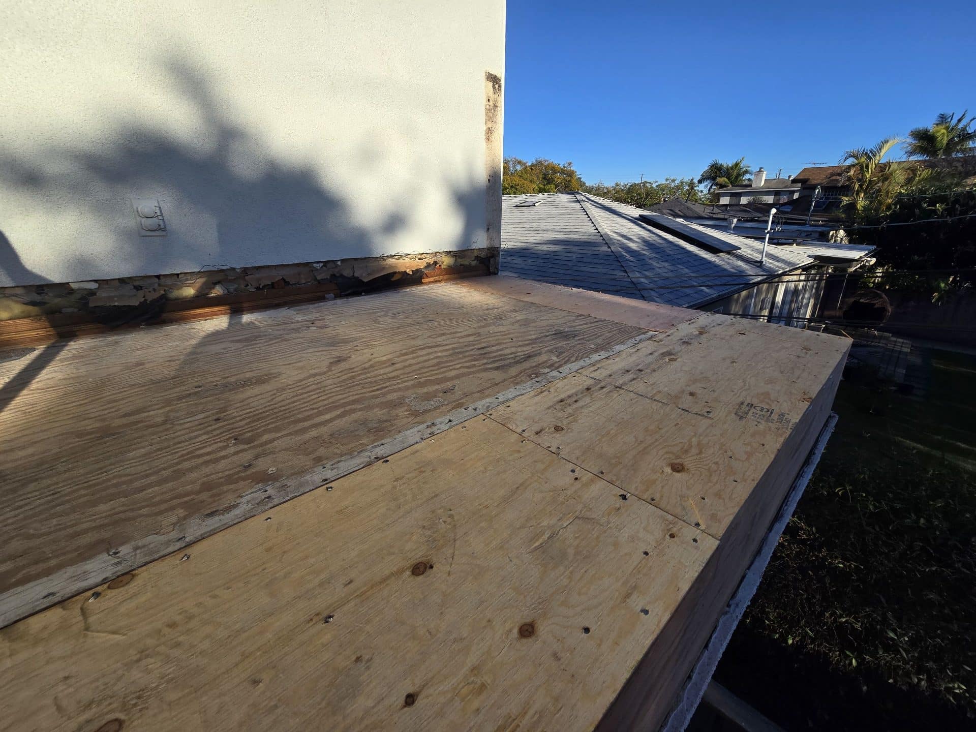 Flat roof plywood decking replacement, damaged fascia and old flashing visible — Roof Replacement Inc