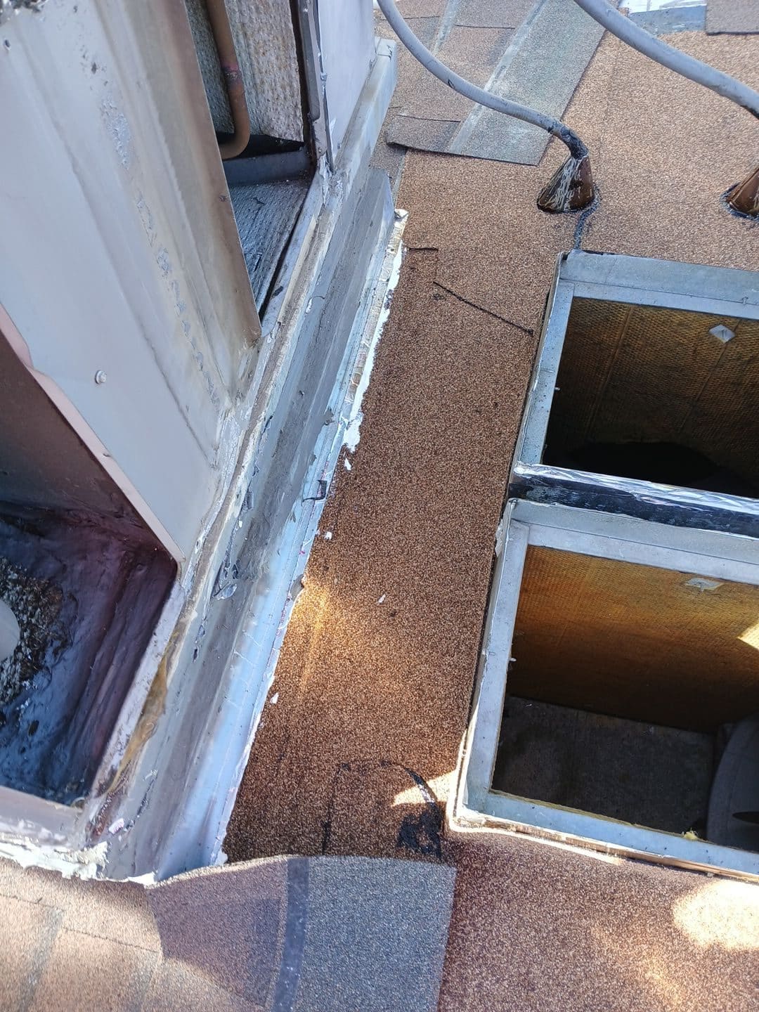 Flat roof section with granule cap sheet, aluminum flashing, and open skylight curbs — Roof Replacement Inc