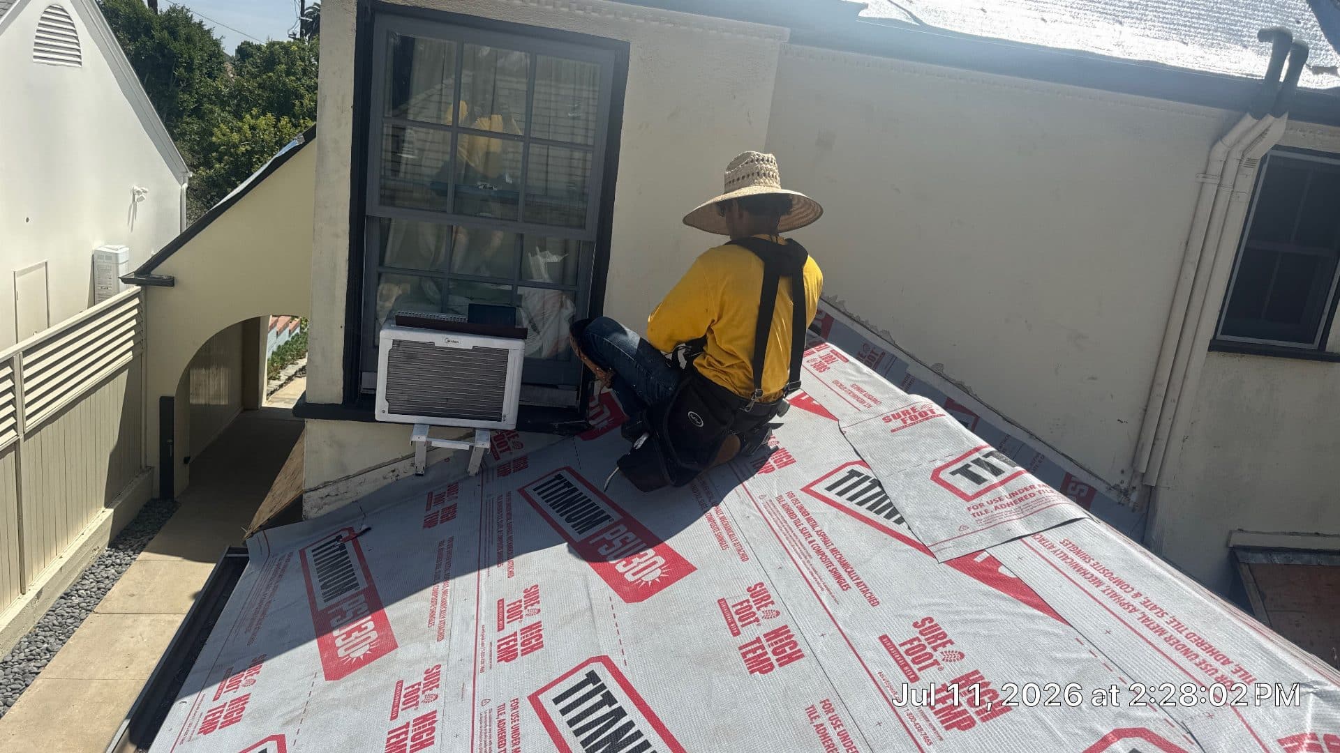 Roofer kneeling on underlayment during flat roof installation | Roof Replacement Inc Roofer kneeling on underlayment during flat roof installation — Roof Replacement Inc