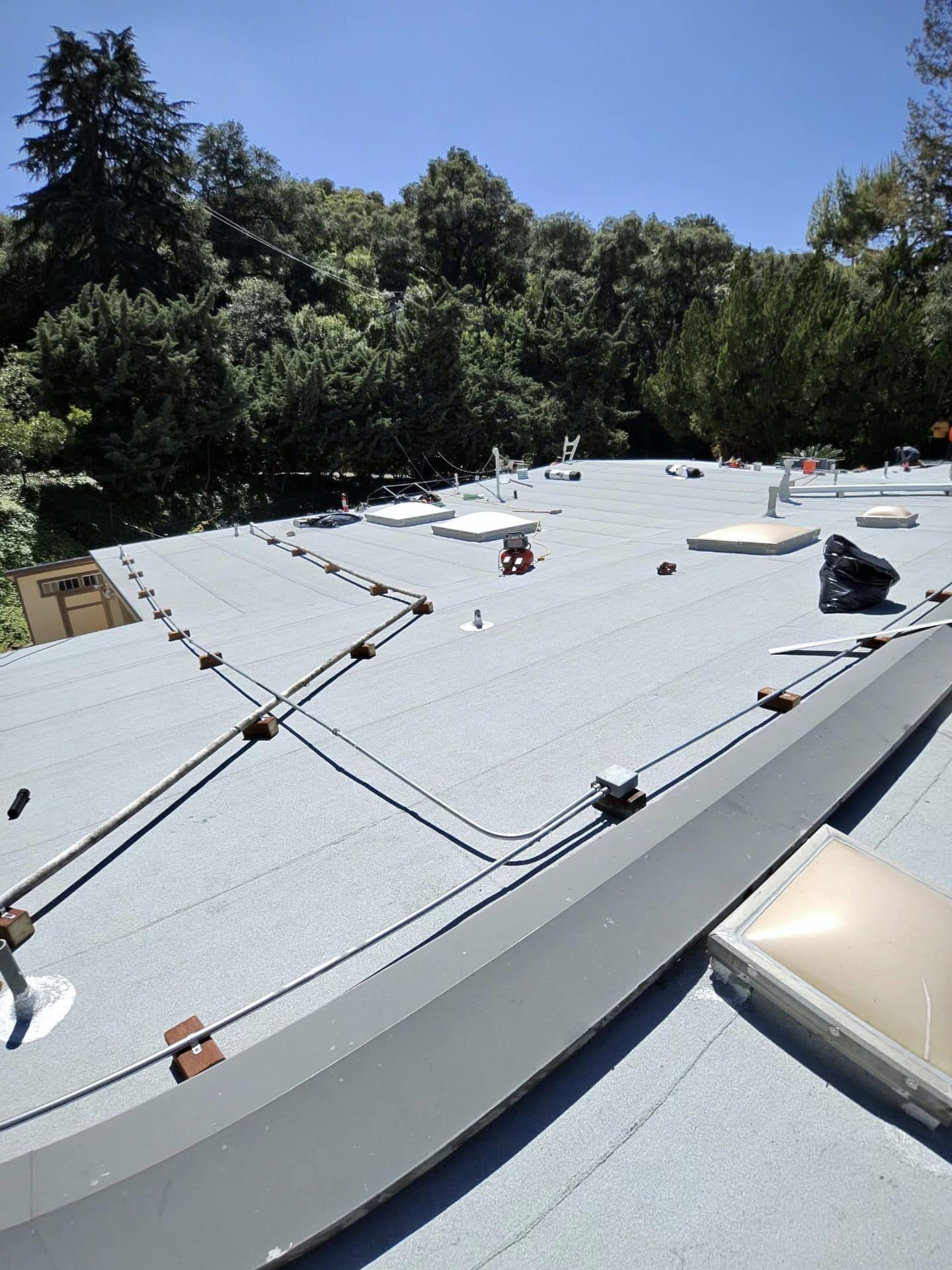 flat roof with TPO membrane, skylights, conduit wiring, and debris — La Cañada Flintridge — Roof Replacement Inc