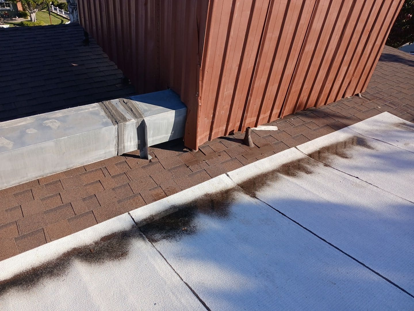 Flat roof foam coating meets brown asphalt shingle slope, metal wall flashing | Roof Replacement Inc Flat roof foam coating meets brown asphalt shingle slope, metal wall flashing — Roof Replacement Inc
