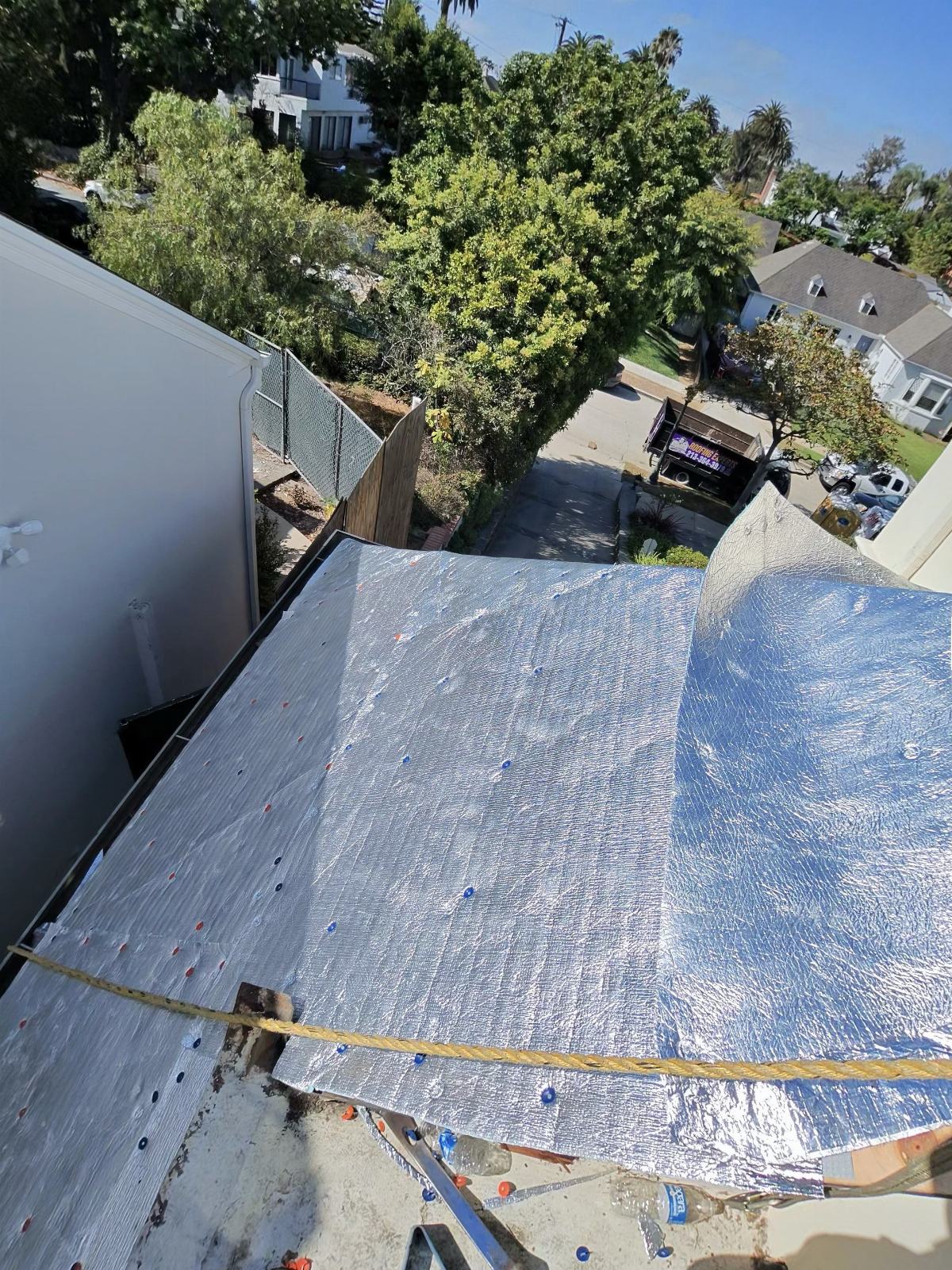 Reflective foil underlayment installed on low-slope roof deck, fastened with cap nails — Roof Replacement Inc
