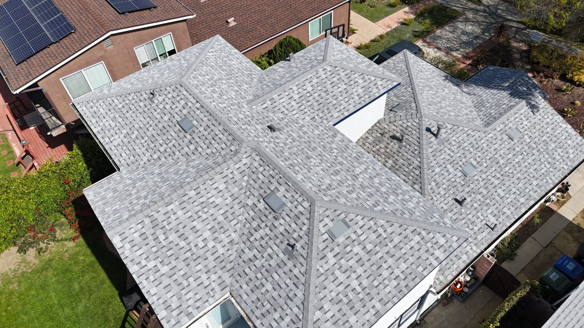 Aerial view of completed gray asphalt shingle hip roof with multiple valleys and vents | Roof Replacement Inc Aerial view of completed gray asphalt shingle hip roof with multiple valleys and vents — Roof Replacement Inc