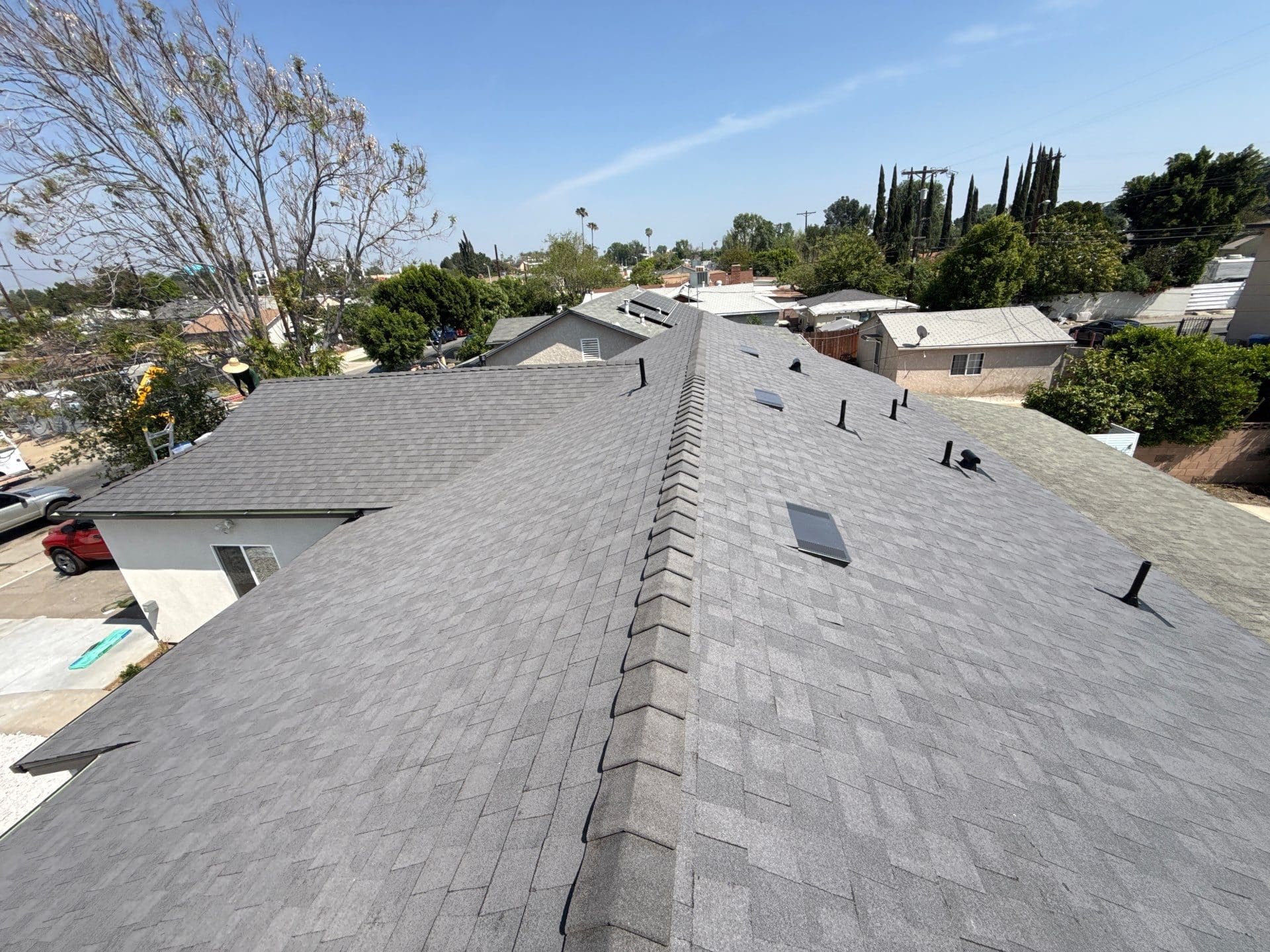 Newly installed gray asphalt shingle roof with ridge cap, skylights, and pipe boots — Roof Replacement Inc