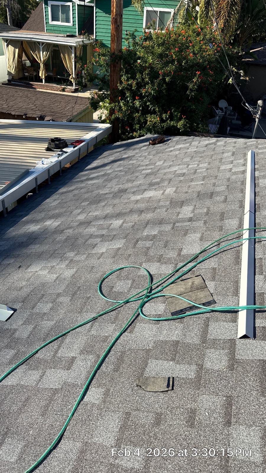 New gray asphalt shingle roof with drip edge and garden hose | Roof Replacement Inc New gray asphalt shingle roof with drip edge and garden hose — Roof Replacement Inc