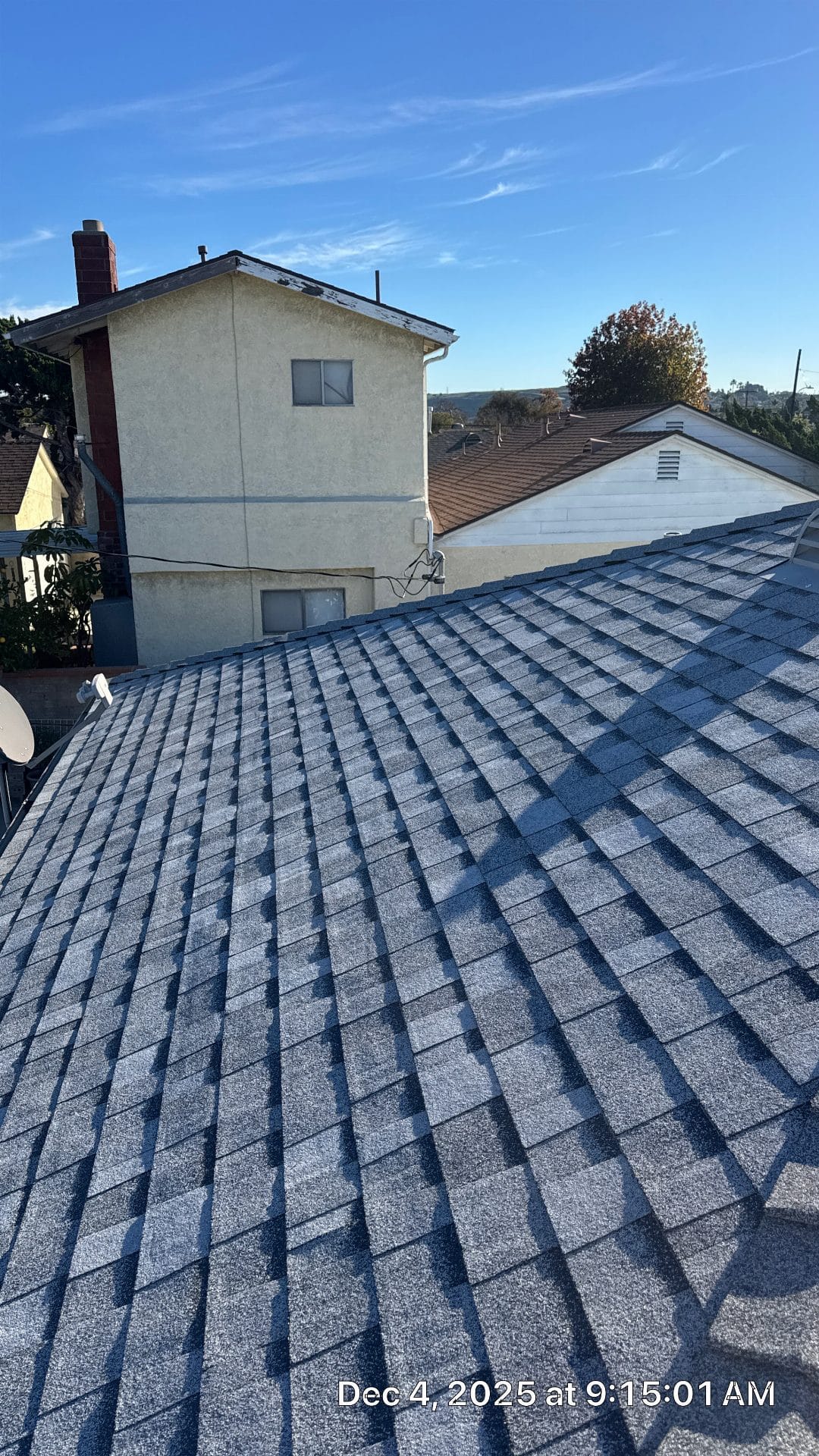 Gray asphalt shingle roof with neighboring stucco buildings visible | Roof Replacement Inc Gray asphalt shingle roof with neighboring stucco buildings visible — Roof Replacement Inc