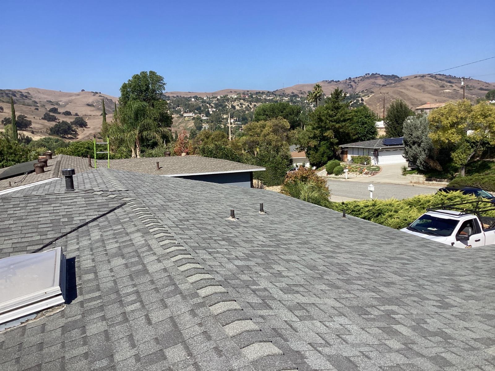 gray asphalt shingle roof with pipe vents skylight and hills — Calabasas — Roof Replacement Inc