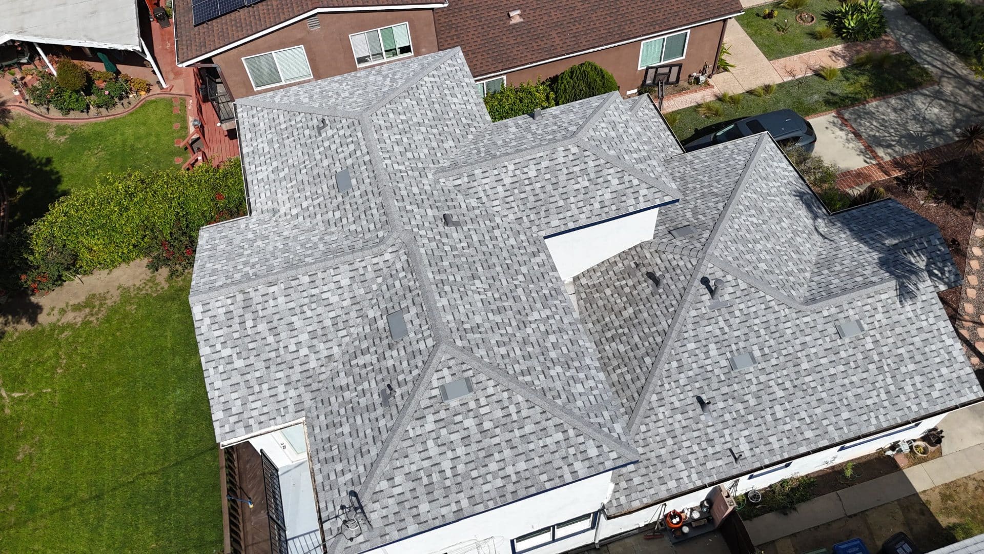 Aerial view of completed grey asphalt shingle hip roof with vents — Roof Replacement Inc