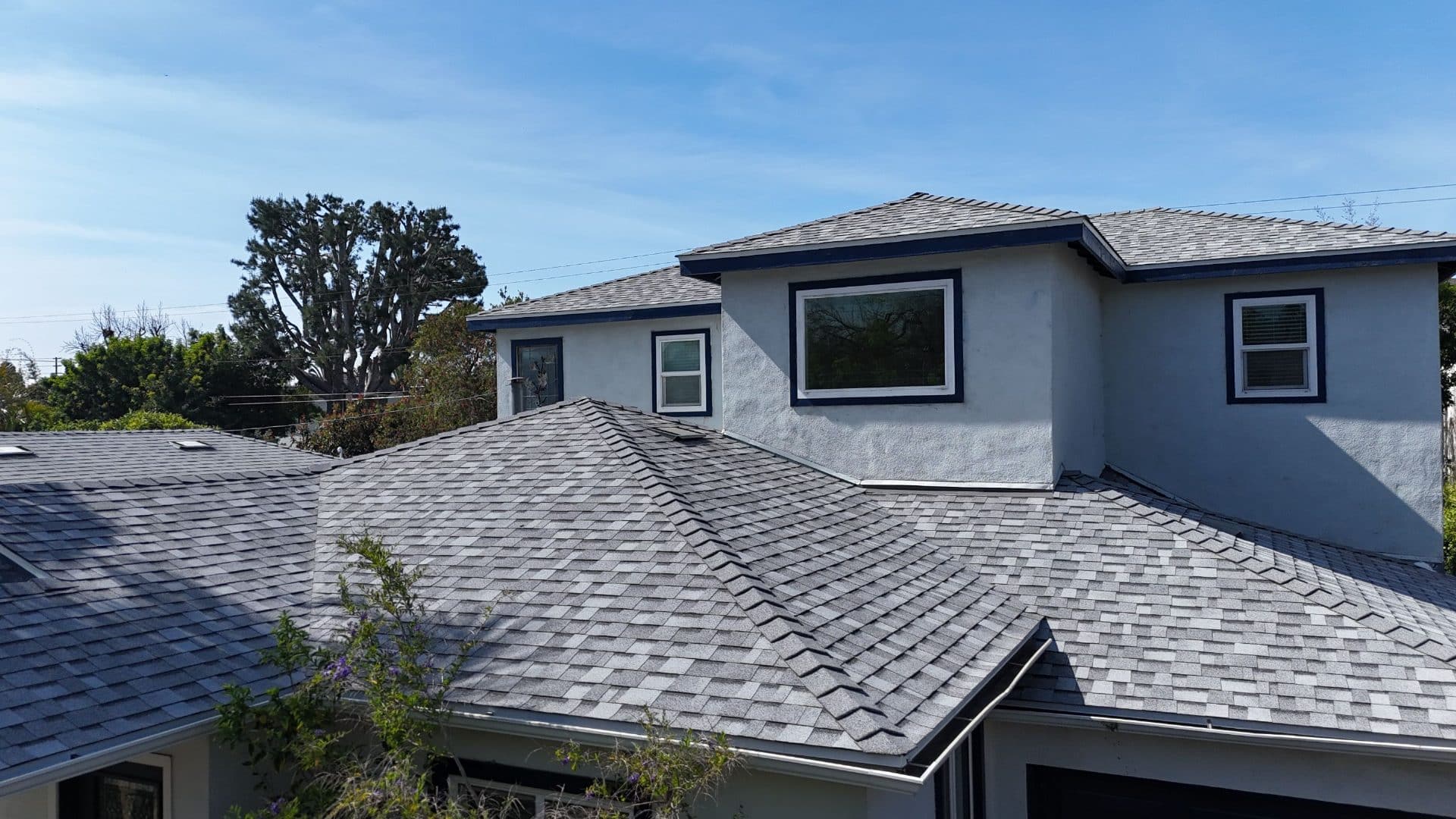 Completed grey asphalt shingle hip roof, stucco second story, gutters | Roof Replacement Inc Completed grey asphalt shingle hip roof, stucco second story, gutters — Roof Replacement Inc