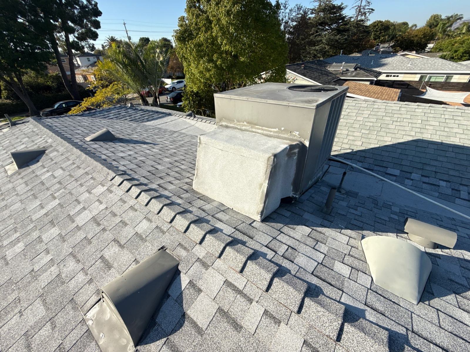 HVAC unit on gray asphalt shingle roof with ventilation caps | Roof Replacement Inc HVAC unit on gray asphalt shingle roof with ventilation caps — Roof Replacement Inc