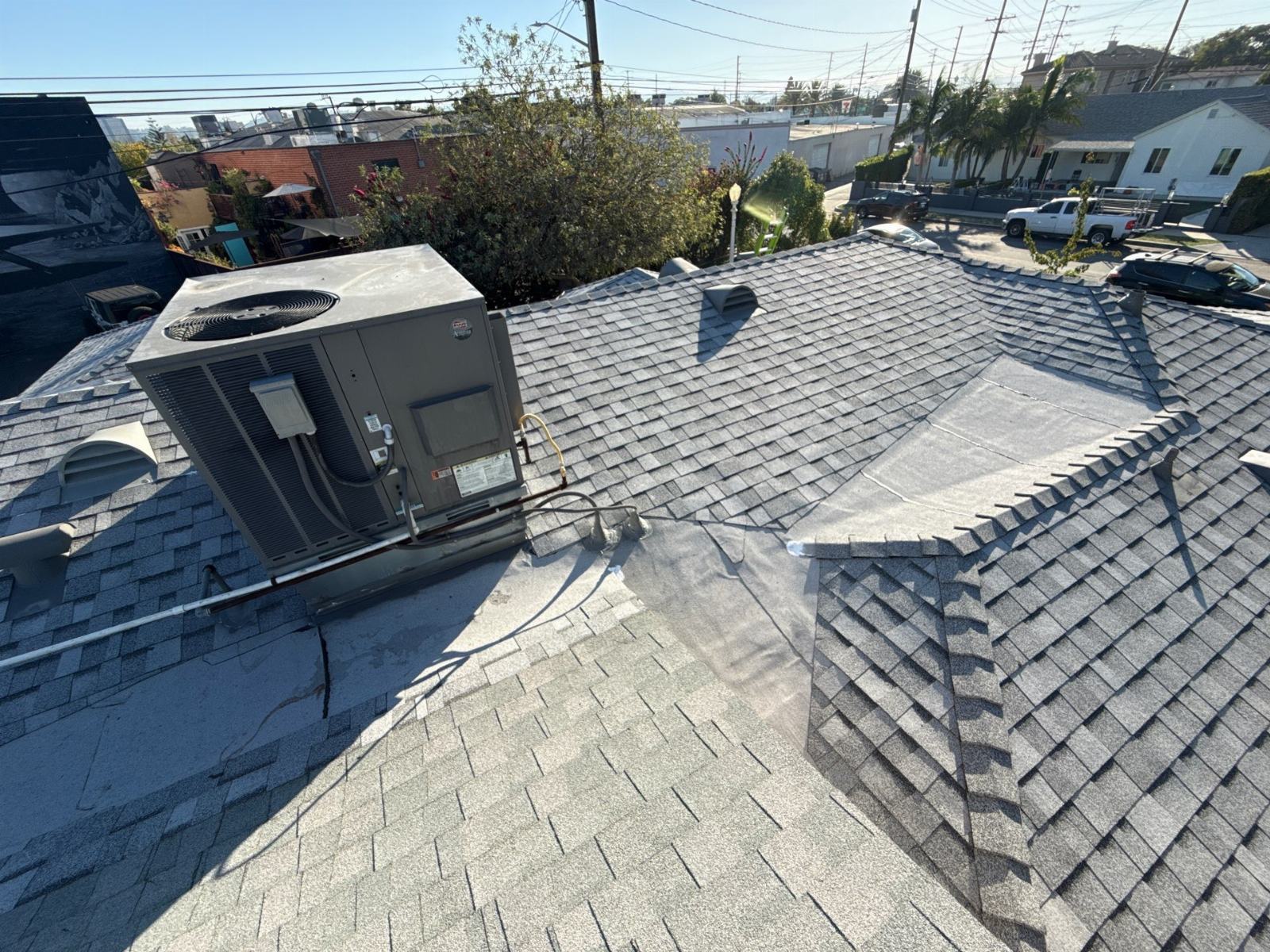 Rooftop HVAC unit on gray asphalt shingle roof with flat section | Roof Replacement Inc rooftop HVAC unit on gray asphalt shingle roof with flat section — Roof Replacement Inc