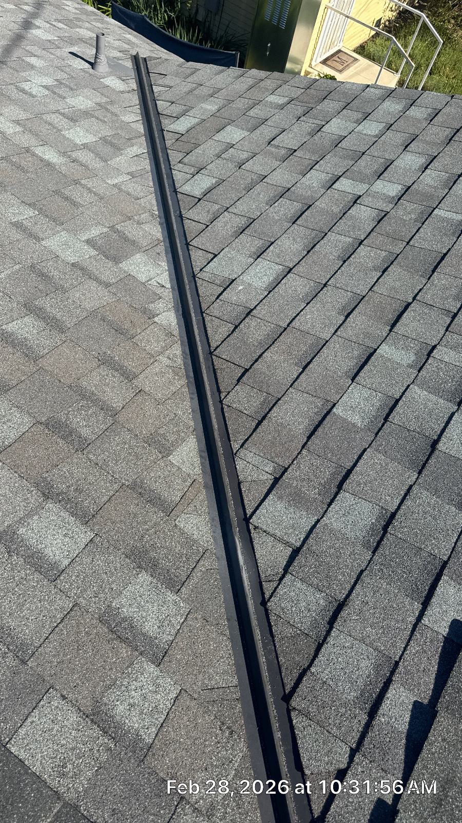 metal hip ridge cap installed over gray asphalt shingle roof — Roof Replacement Inc