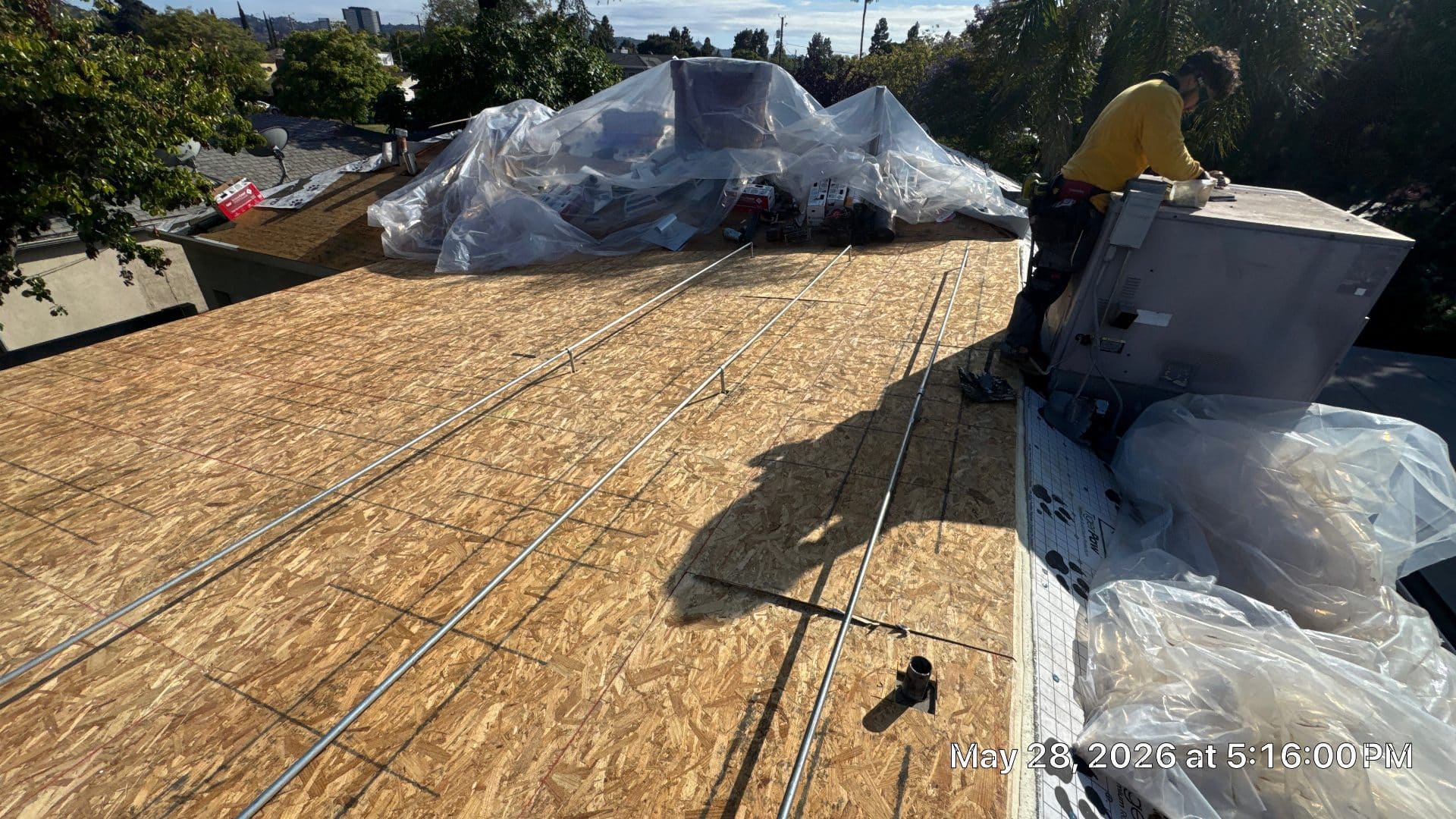 Worker installs conduit on exposed OSB roof decking with HVAC unit | Roof Replacement Inc Worker installs conduit on exposed OSB roof decking with HVAC unit — Roof Replacement Inc
