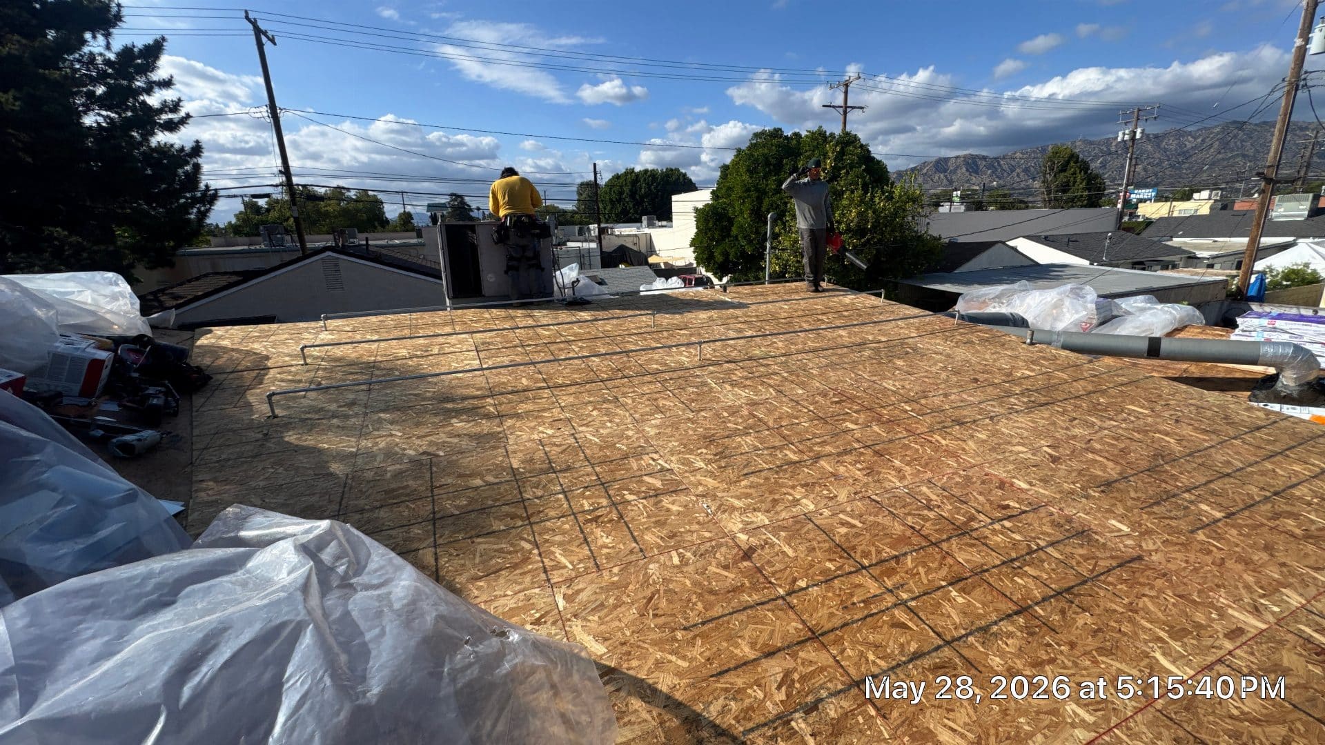 Workers installing OSB sheathing on flat commercial roof deck | Roof Replacement Inc Workers installing OSB sheathing on flat commercial roof deck — Roof Replacement Inc