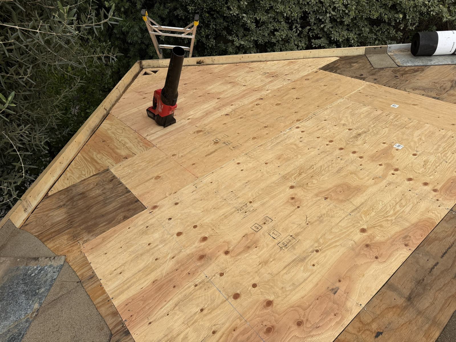New plywood sheathing installed on flat roof deck with Milwaukee drill | Roof Replacement Inc New plywood sheathing installed on flat roof deck with Milwaukee drill — Roof Replacement Inc