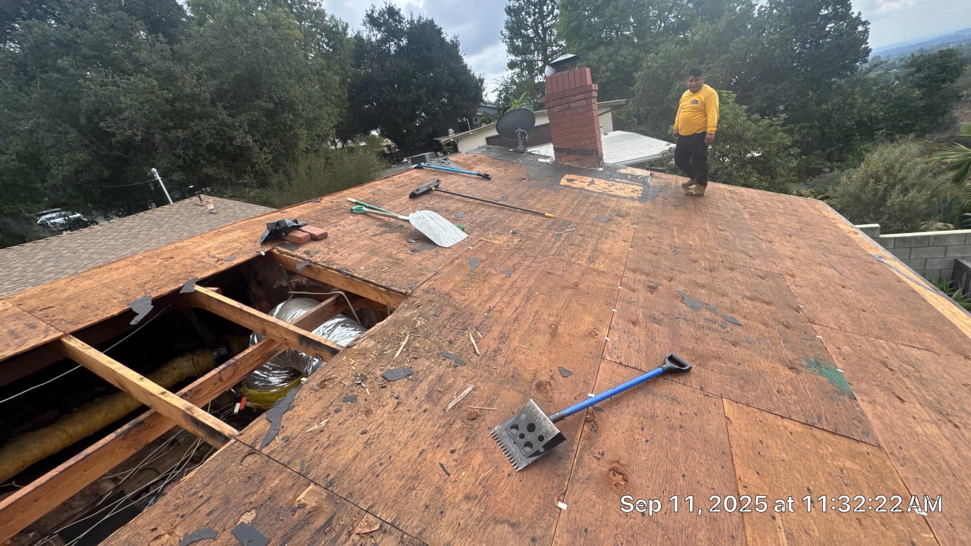Worker on stripped plywood roof deck, open sheathing hole, HVAC duct exposed in Altadena | Roof Replacement Inc worker on stripped plywood roof deck, open sheathing hole, HVAC duct exposed — Altadena — Roof Replacement Inc