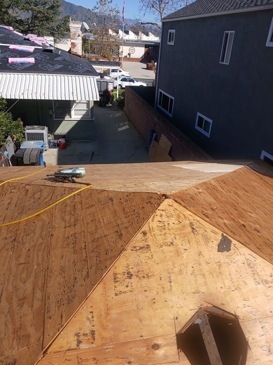 Plywood roof sheathing installation on hip roof, nail gun visible | Roof Replacement Inc plywood roof sheathing installation on hip roof, nail gun visible — Roof Replacement Inc