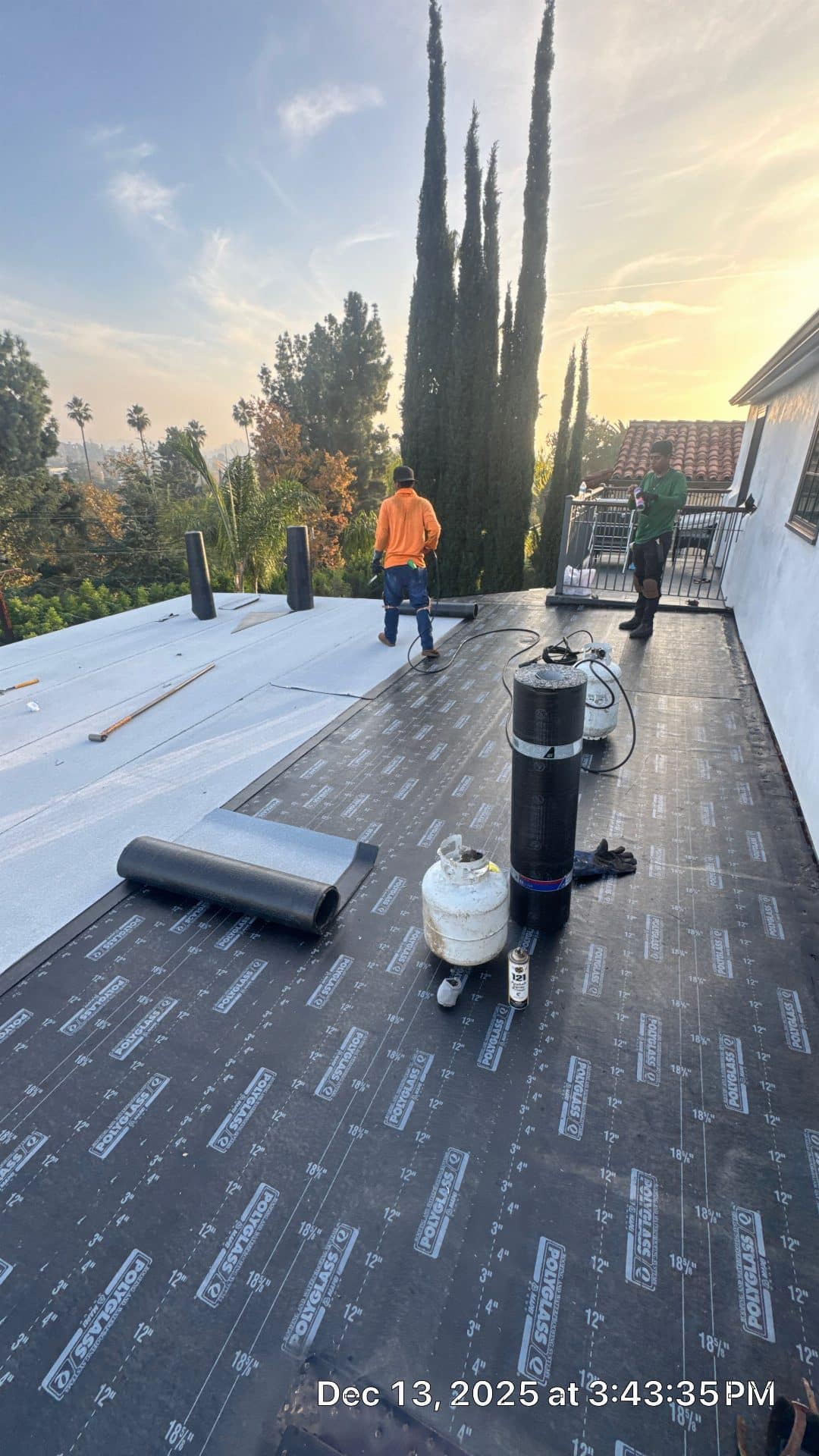 Two roofers installing Polyglass torch-down modified bitumen on flat roof — Glendale — Roof Replacement Inc