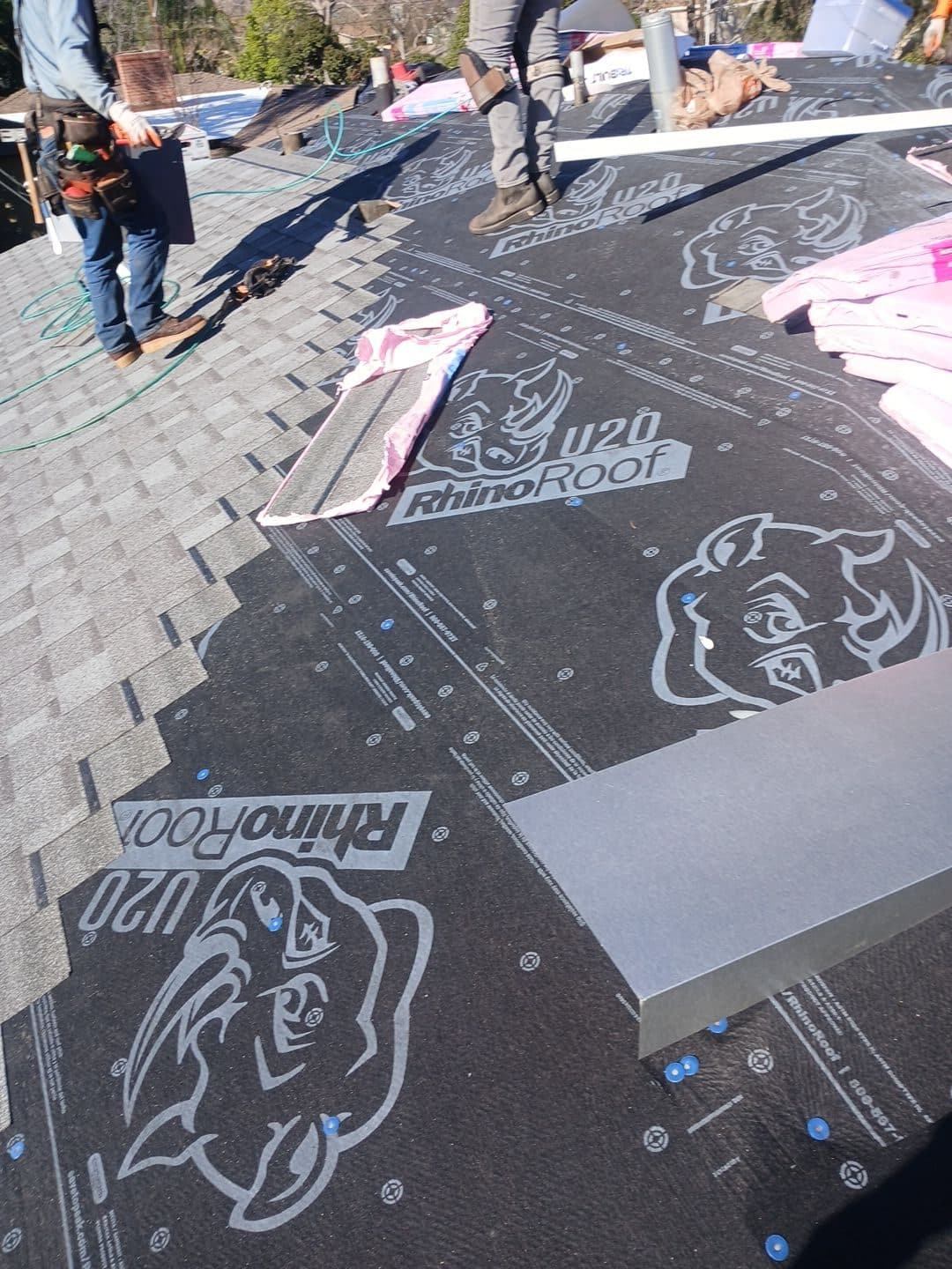 Workers installing RhinoRoof U20 synthetic underlayment on residential roof deck — Roof Replacement Inc
