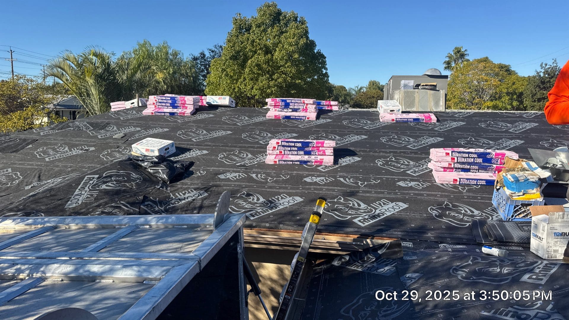 RhinoRoof underlayment installed with Duration Cool shingle bundles staged on deck — Roof Replacement Inc
