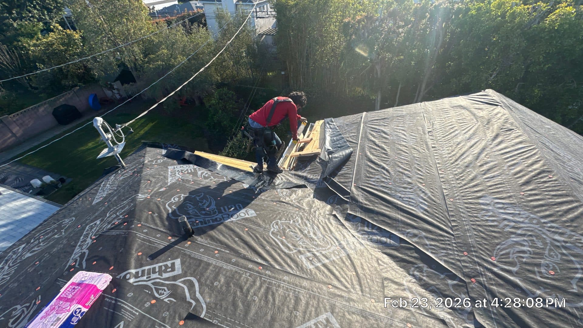 Worker installing RhinoRoof U20 underlayment on steep residential roof deck | Roof Replacement Inc Worker installing RhinoRoof U20 underlayment on steep residential roof deck — Roof Replacement Inc
