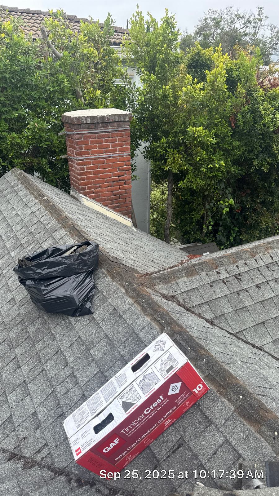 GAF TimberCrest ridge cap box and debris bag on aging asphalt shingle roof near brick chimney in Beverly Hills | Roof Replacement Inc GAF TimberCrest ridge cap box and debris bag on aging asphalt shingle roof near brick chimney — Beverly Hills