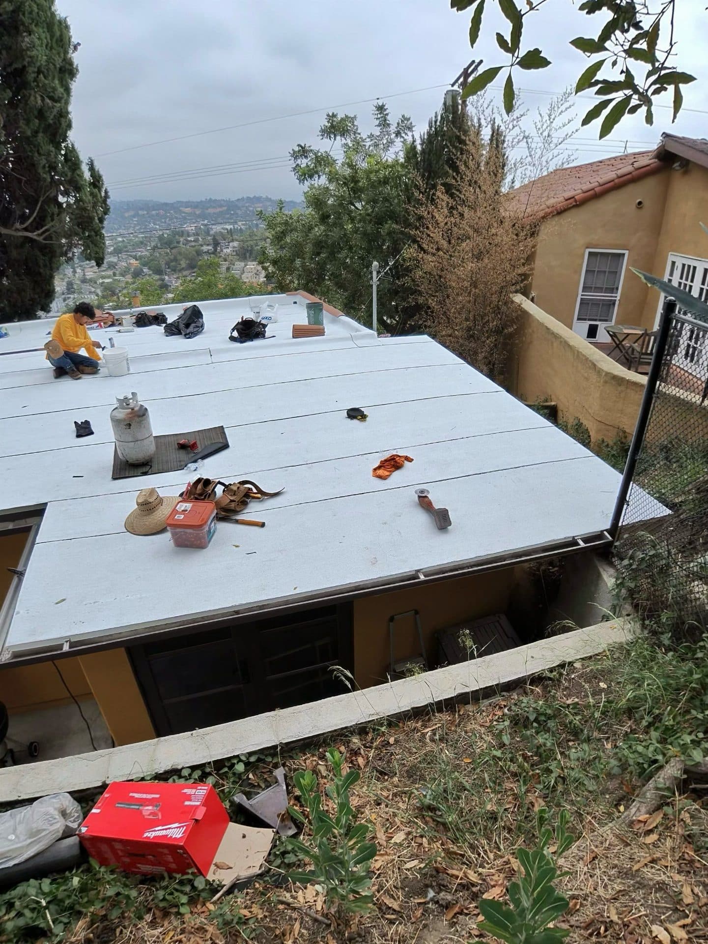 Worker installing white TPO flat roof membrane with propane torch in North Hollywood | Roof Replacement Inc worker installing white TPO flat roof membrane with propane torch — North Hollywood — Roof Replacement Inc