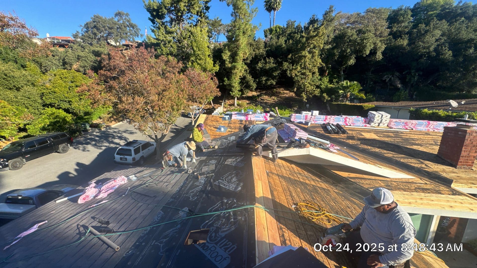 Crew installing underlayment on wood deck roof, shingle bundles staged nearby | Roof Replacement Inc Crew installing underlayment on wood deck roof, shingle bundles staged nearby — Roof Replacement Inc
