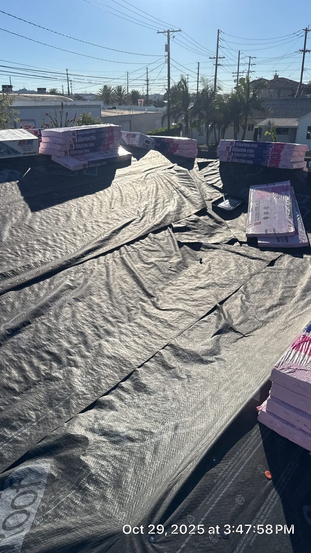 roofing underlayment laid flat with stacked shingle bundles on deck — Roof Replacement Inc