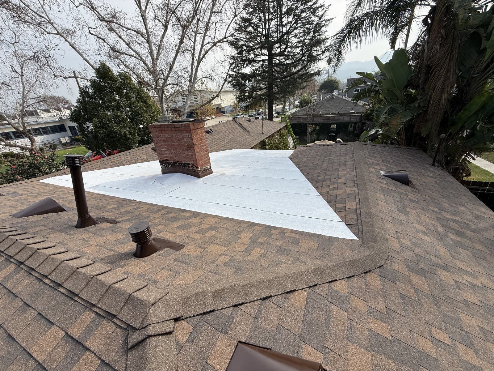 asphalt shingle roof with white underlayment patch and brick chimney — Burbank — Roof Replacement Inc