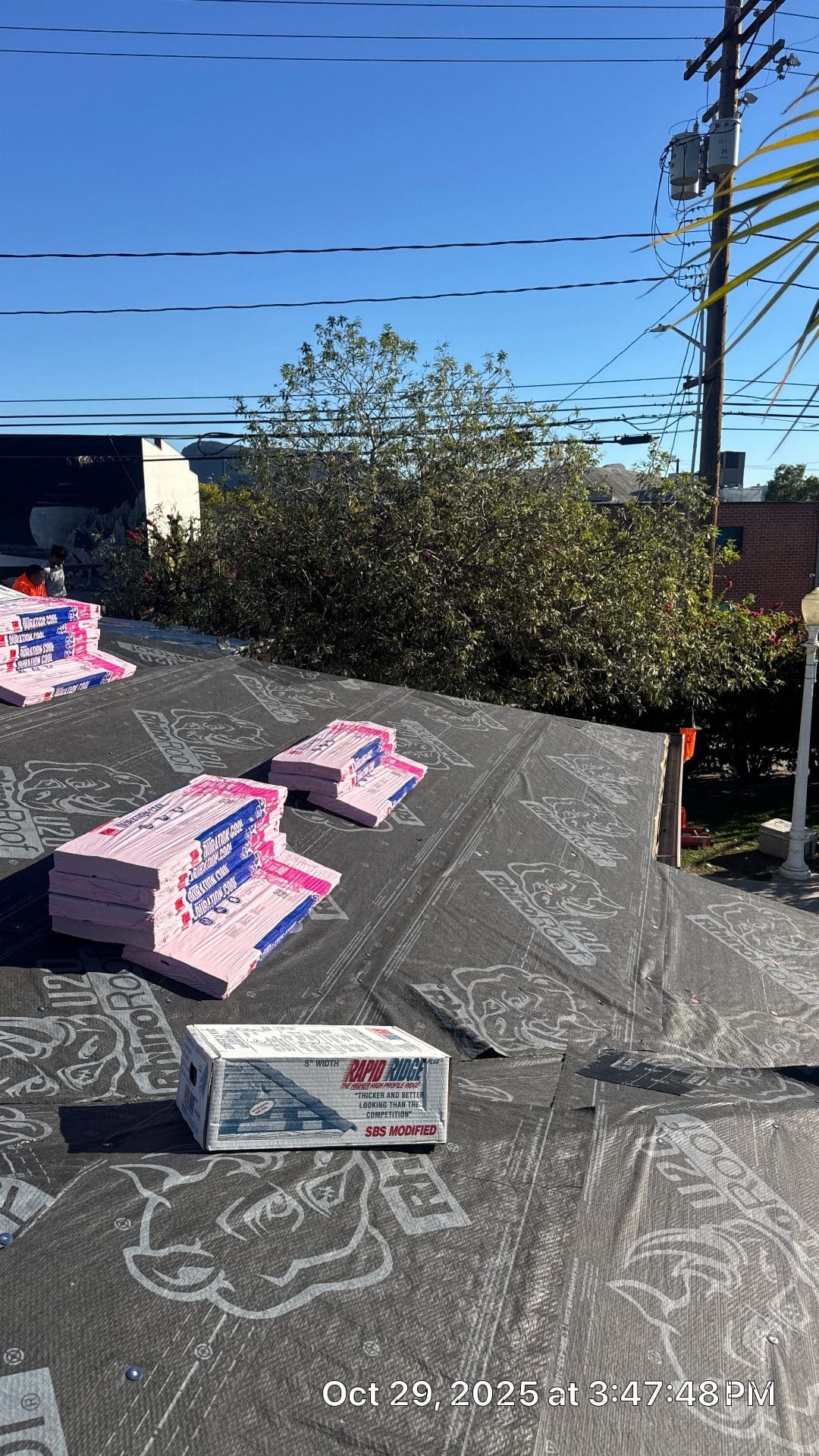 GAF shingles and Rapid Ridge cap stacked on underlayment-covered roof deck — Roof Replacement Inc