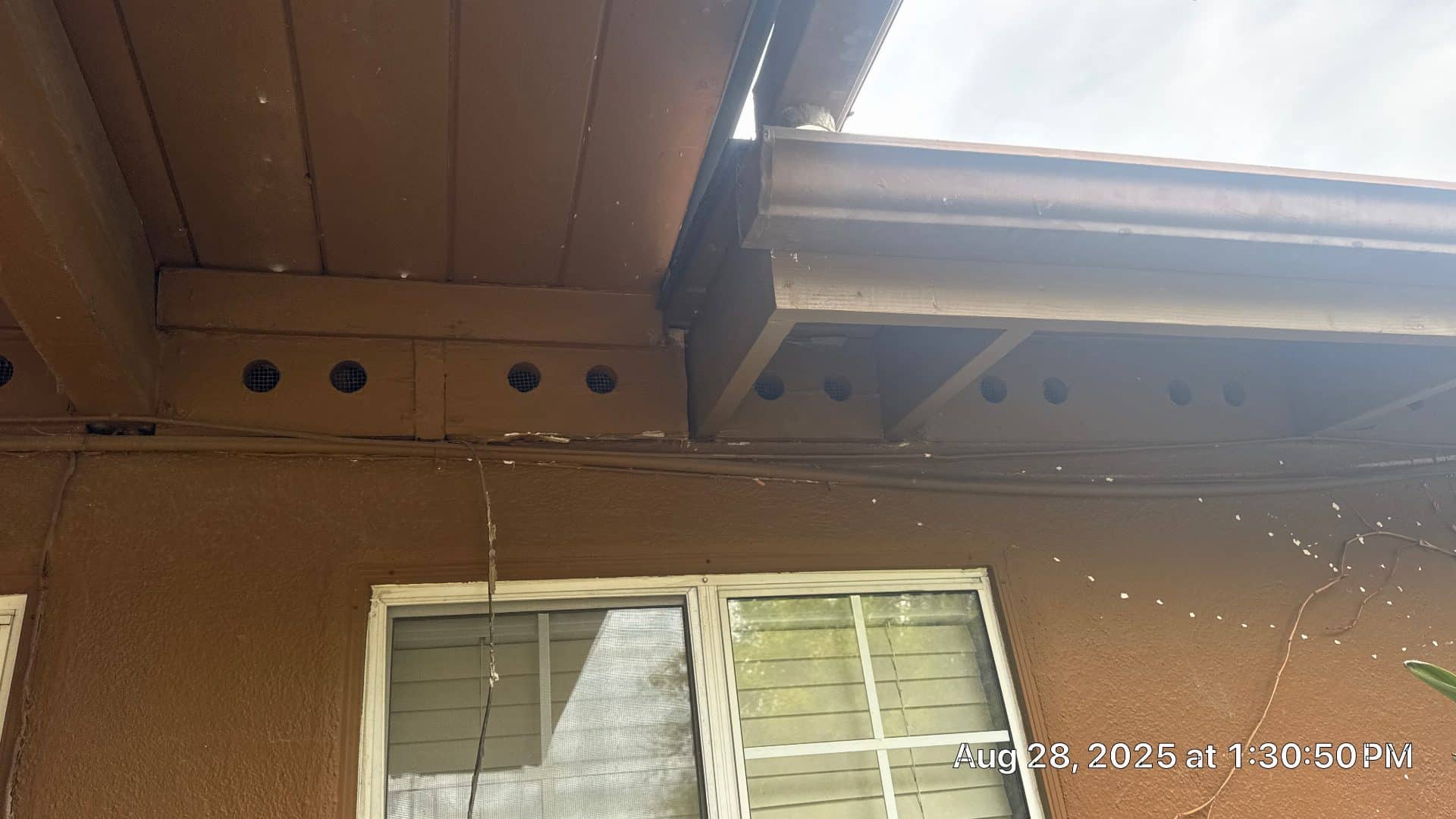 Soffit vents, fascia board, and rain gutter on stucco exterior | Roof Replacement Inc Soffit vents, fascia board, and rain gutter on stucco exterior — Roof Replacement Inc