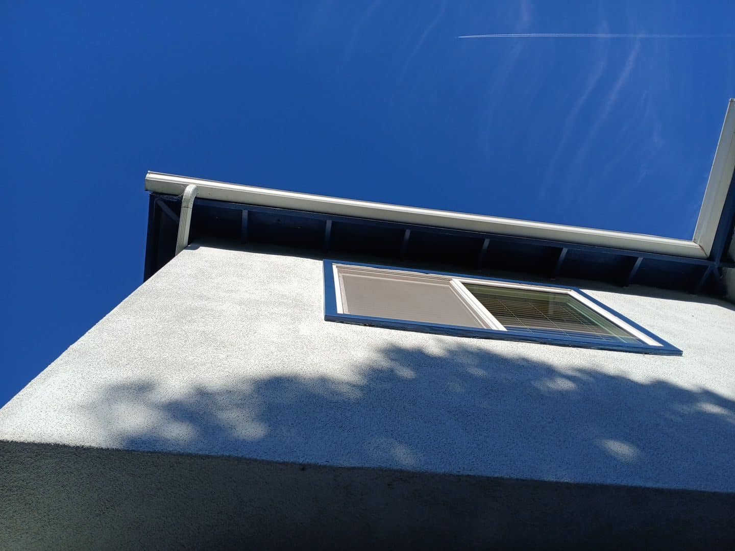 Stucco wall corner, eave soffit, gutters, and upper window | Roof Replacement Inc Stucco wall corner, eave soffit, gutters, and upper window — Roof Replacement Inc