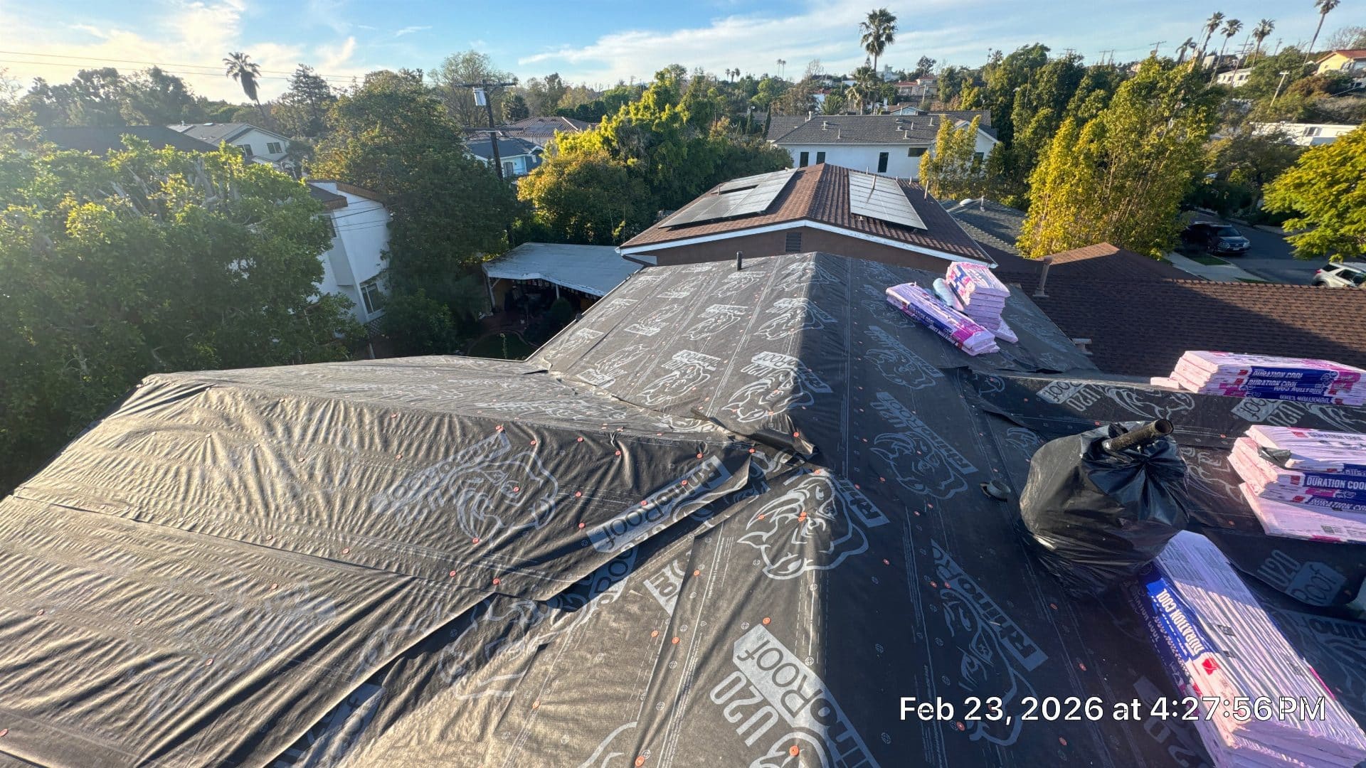 Roof deck covered with synthetic underlayment, shingle bundles staged nearby | Roof Replacement Inc Roof deck covered with synthetic underlayment, shingle bundles staged nearby — Roof Replacement Inc