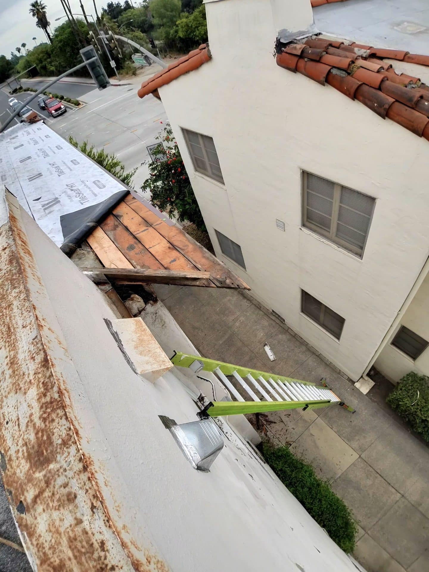 Aerial view of flat and tile roof re-roofing, exposed decking, underlayment, green ladder — Roof Replacement Inc