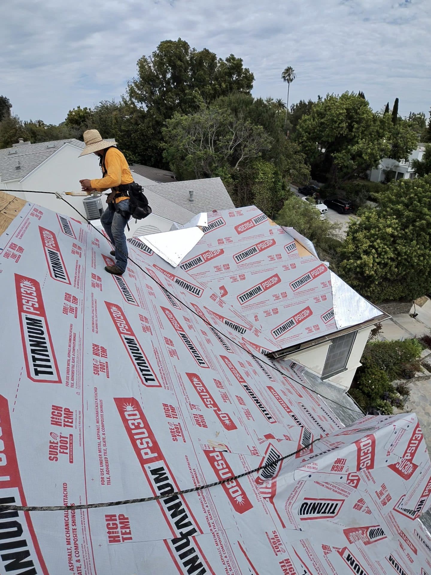 Roofer walking on Titanium PSU30 underlayment over pitched roof deck | Roof Replacement Inc Roofer walking on Titanium PSU30 underlayment over pitched roof deck — Roof Replacement Inc